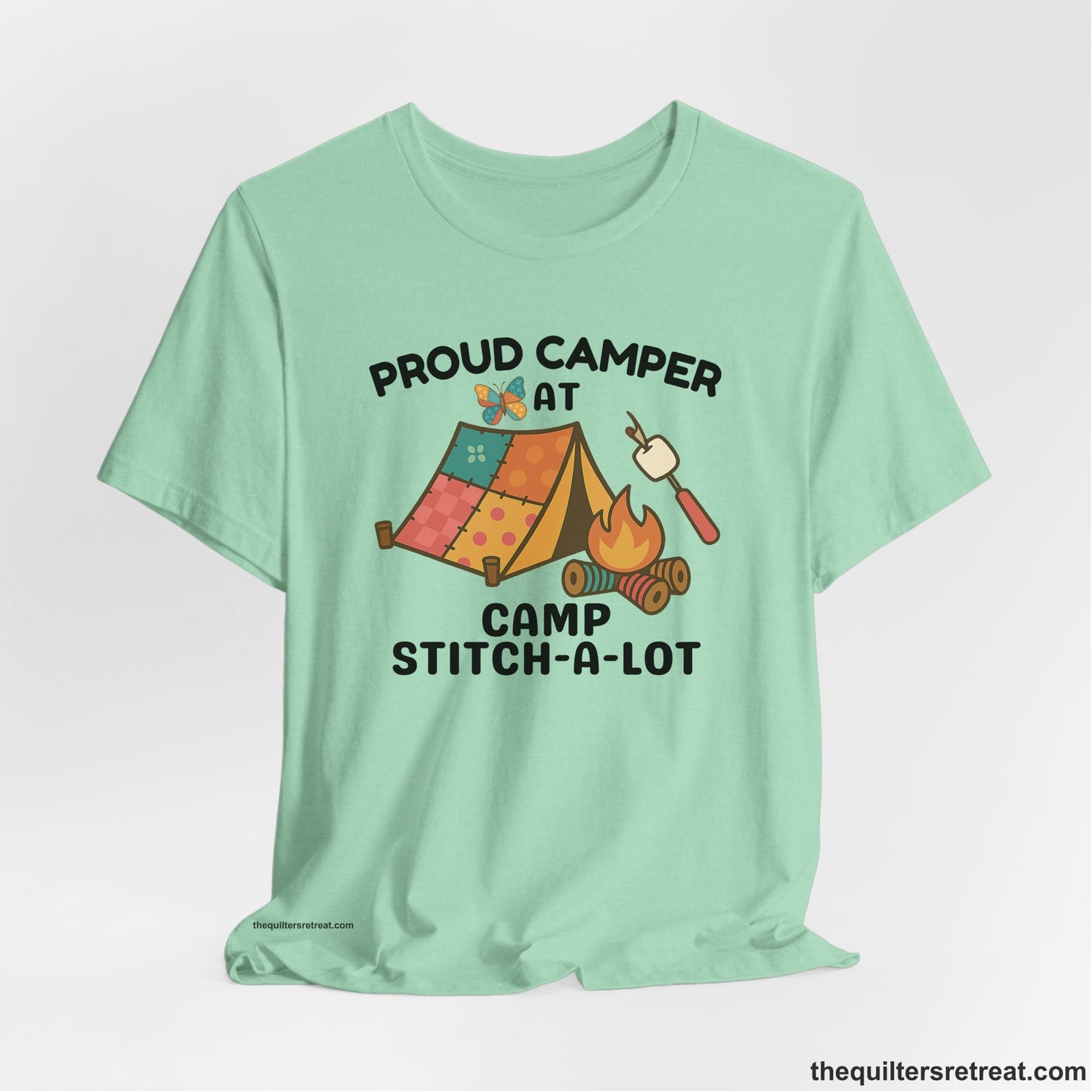 A Heather Mint Short Sleeve T-Shirt with a camping scene with patchwork tent, campfire, and whimsical butterfly and marshmallow illustration