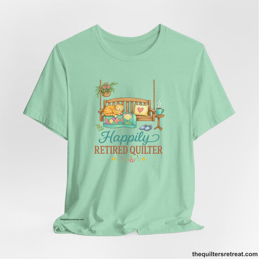 A Short Sleeve T-Shirt with a hanging bench with cozy cat and quilt, surrounded by plants, "Happily Retired Quilter" text