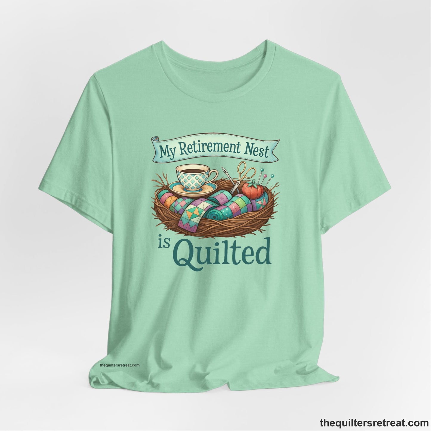 A Heather Mint Short Sleeve T-Shirt with a My Retirement Nest is Quilted text with a cozy sewing elements illustration