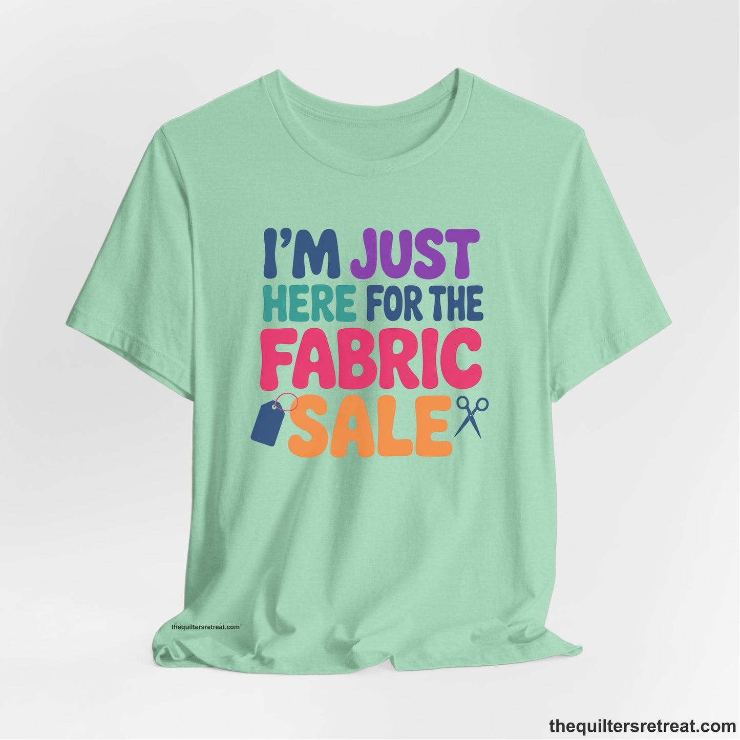 A Heather Mint Short Sleeve T-Shirt with a playful "I'm Just Here for the Fabric Sale" text with colorful letters and sewing icons