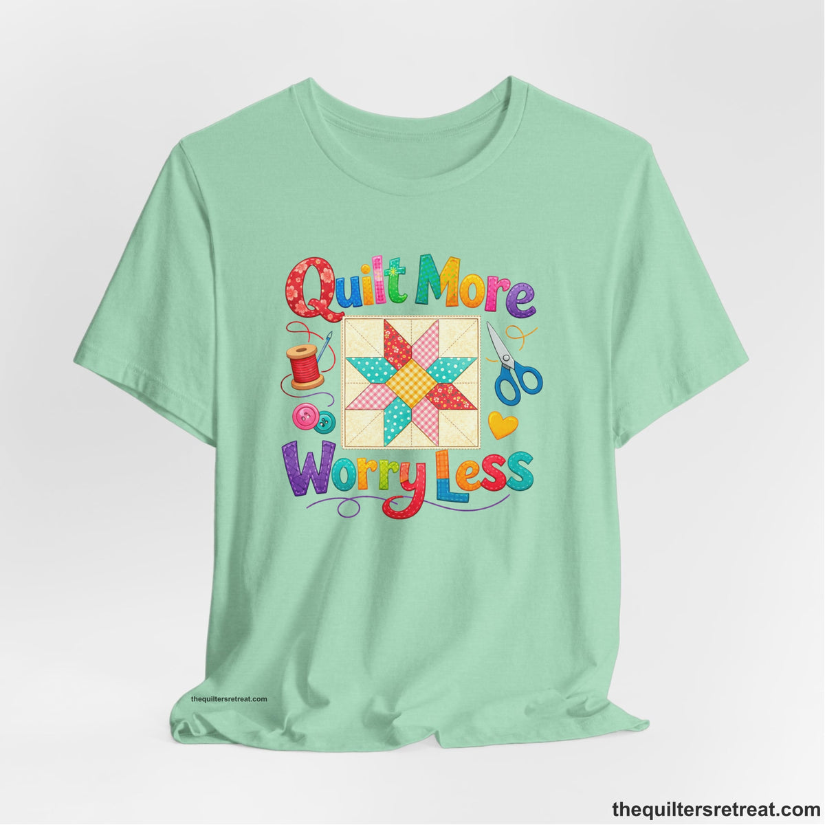 A Heather Mint Short Sleeve T-Shirt with a Colorful patchwork star and sewing tools, cheerful "Quilt More Worry Less" text.