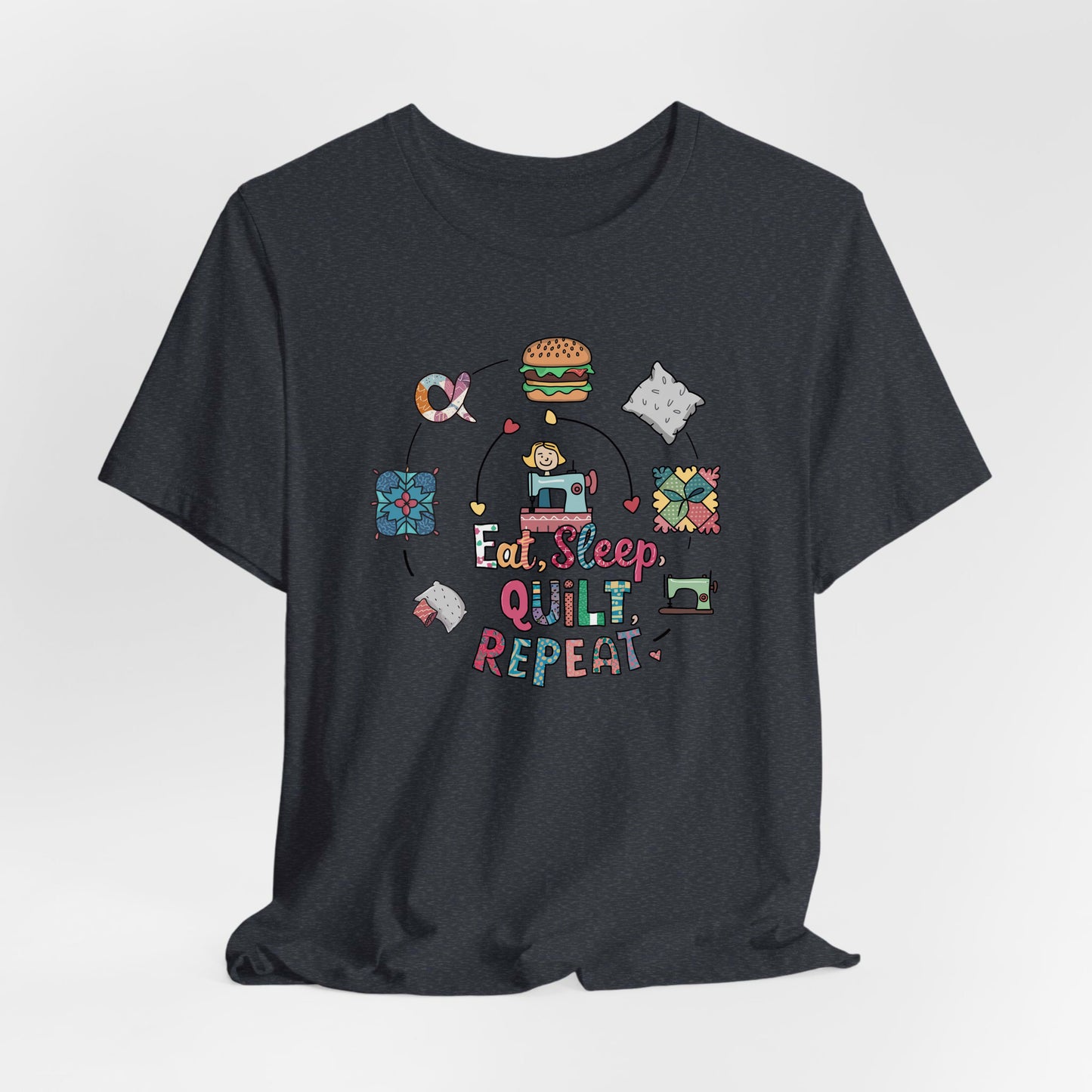 A Heather Navy Short Sleeve T-Shirt with a cute quilting elements with "Eat, Sleep, Quilt, Repeat" text in playful style
