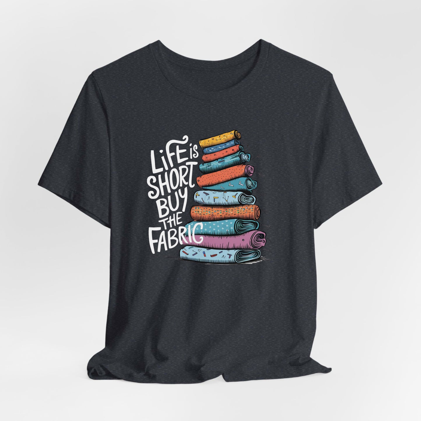 A Heather Navy Short Sleeve T-Shirt with a illustration of colorful fabric rolls with bold "Life is Short Buy the Fabric" text