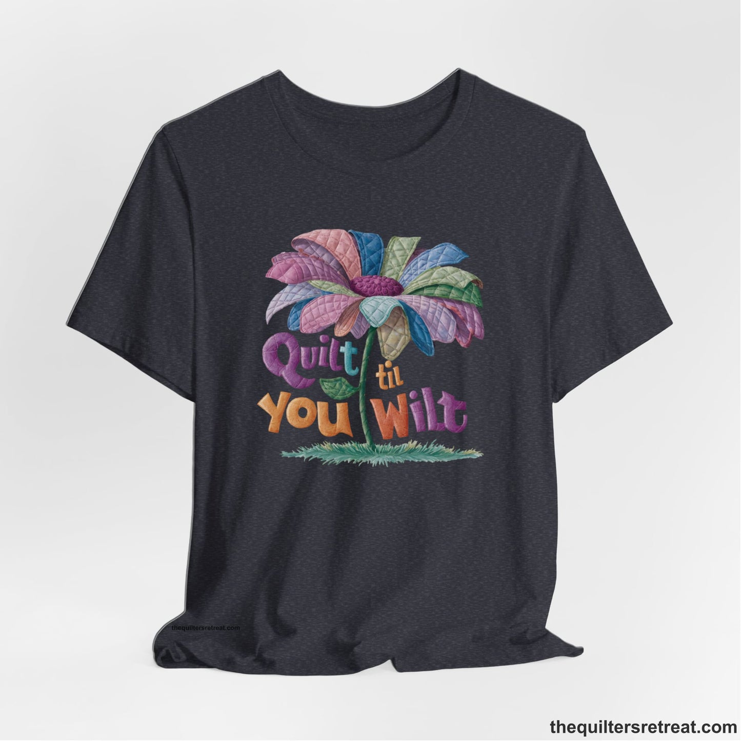A Heather Navy Short Sleeve T-Shirt with a whimsical quilted flower with bold "Quilt til You Wilt" text