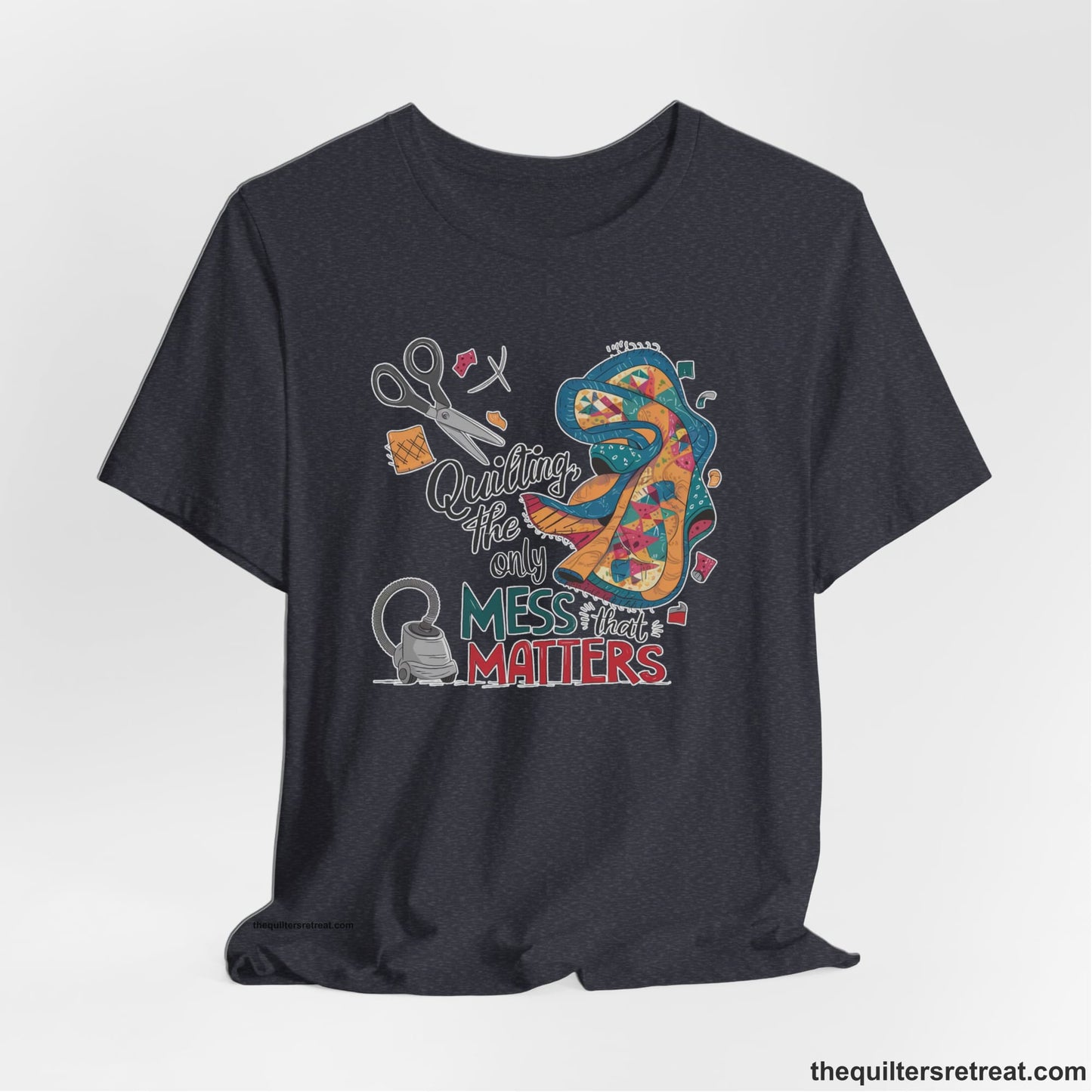 A Heather Navy Short Sleeve T-Shirt with a quilting tools and patchwork pieces with bold "Quilting, the only mess that matters" text