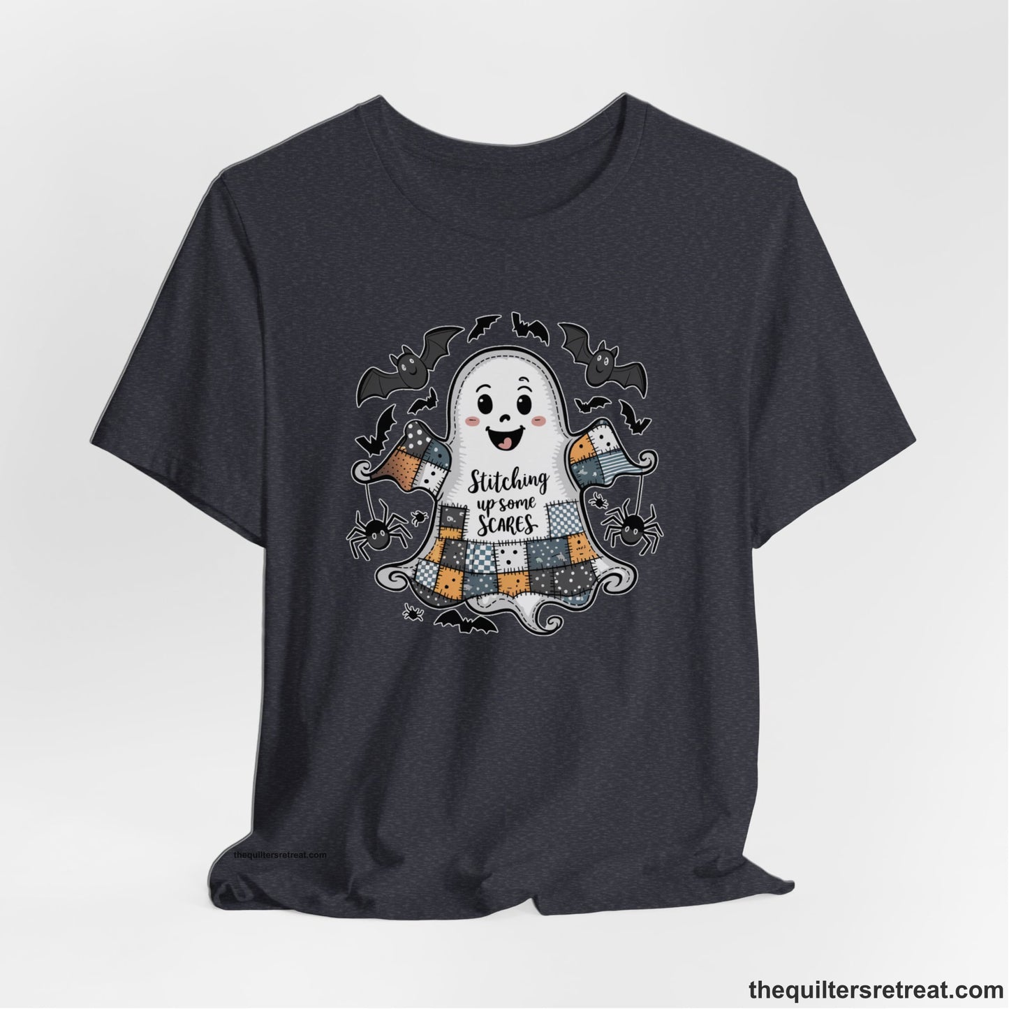 A Heather Navy Short Sleeve T-Shirt with a cute patchwork ghost with "Stitching up some Scares" text and playful bats in a whimsical style