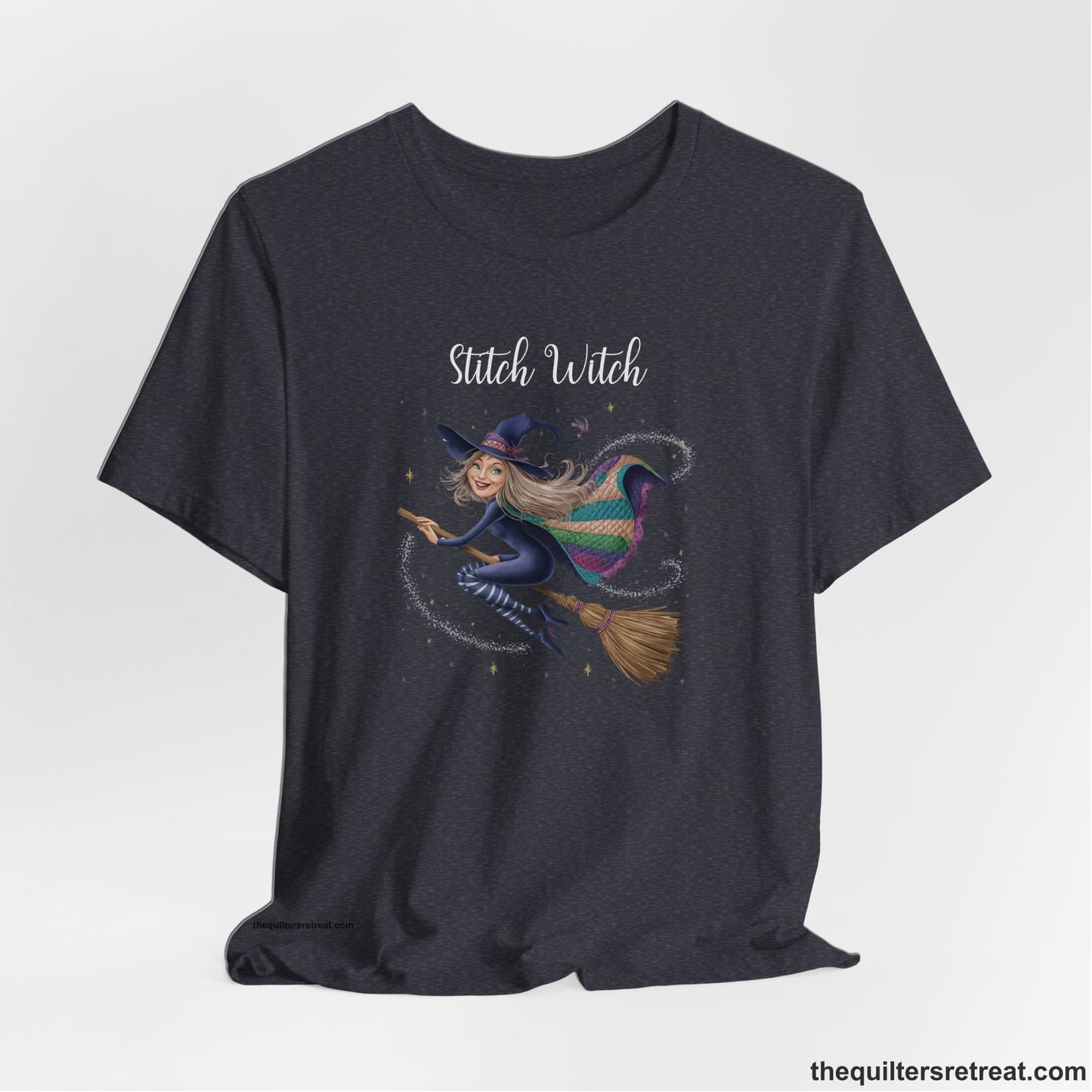 A Heather Navy Short Sleeve T-Shirt with a playful witch on broomstick with patchwork cape and starry background in a whimsical style