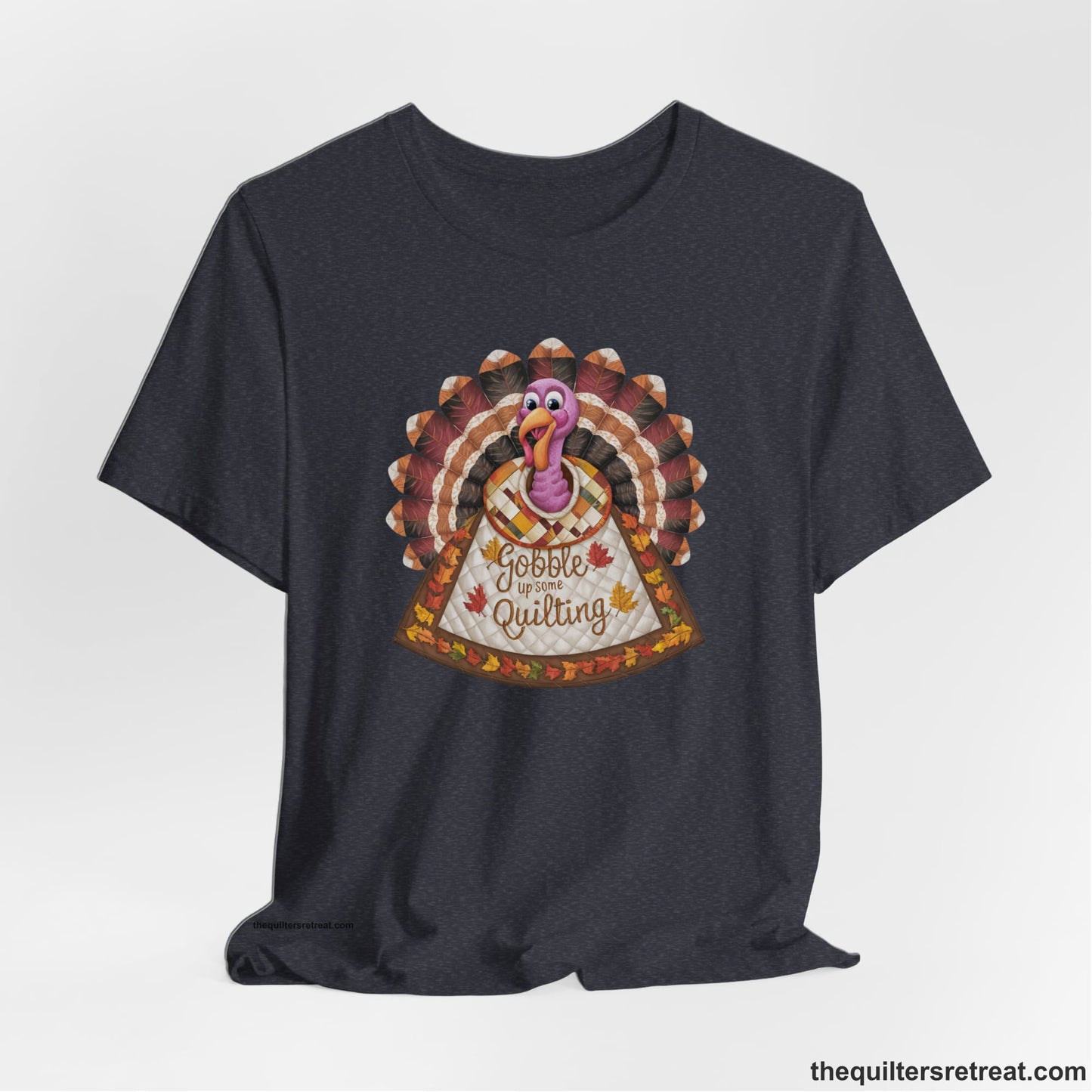 A Heather Navy Short Sleeve T-Shirt with a colorful turkey with quilted feathers and "Gobble Up Some Quilting" text in a playful style