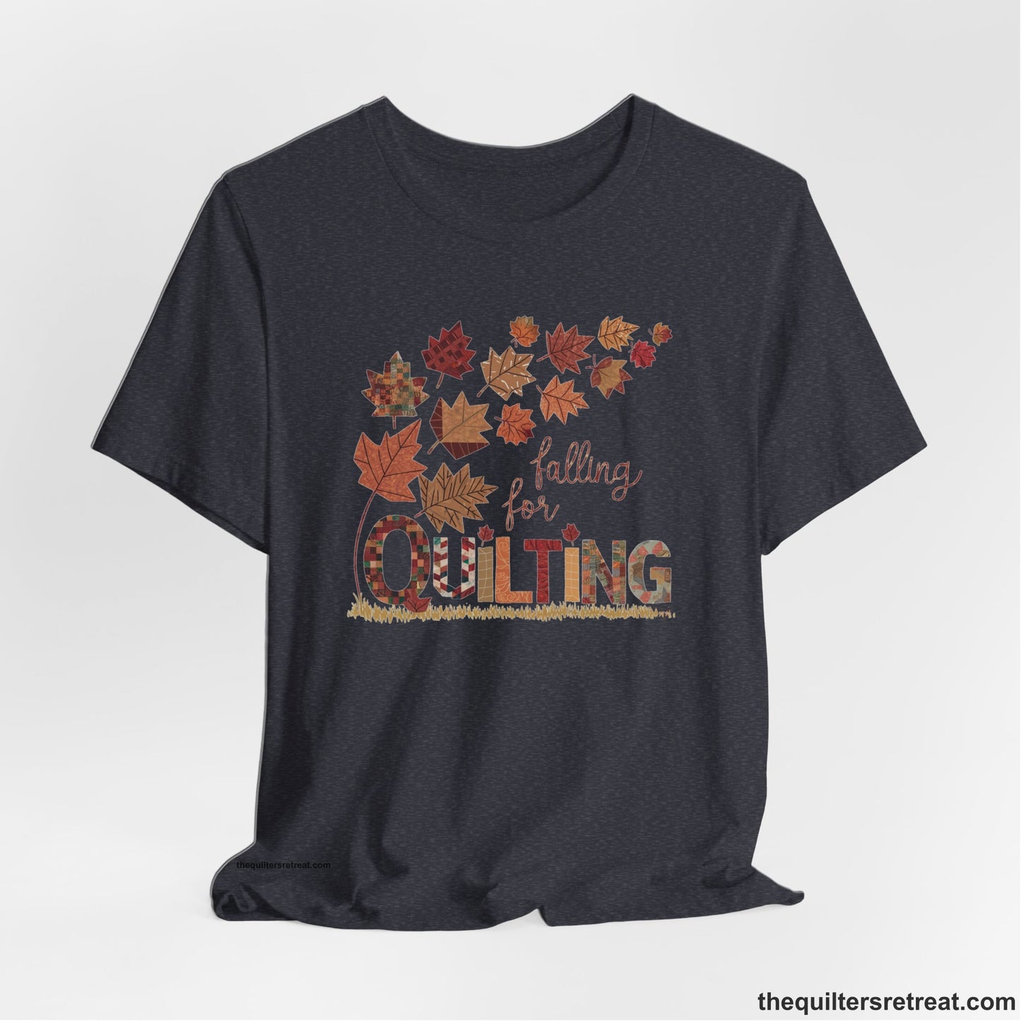 A Heather Navy Short Sleeve T-Shirt with a falling autumn leaves and "Falling for Quilting" text in a patchwork style