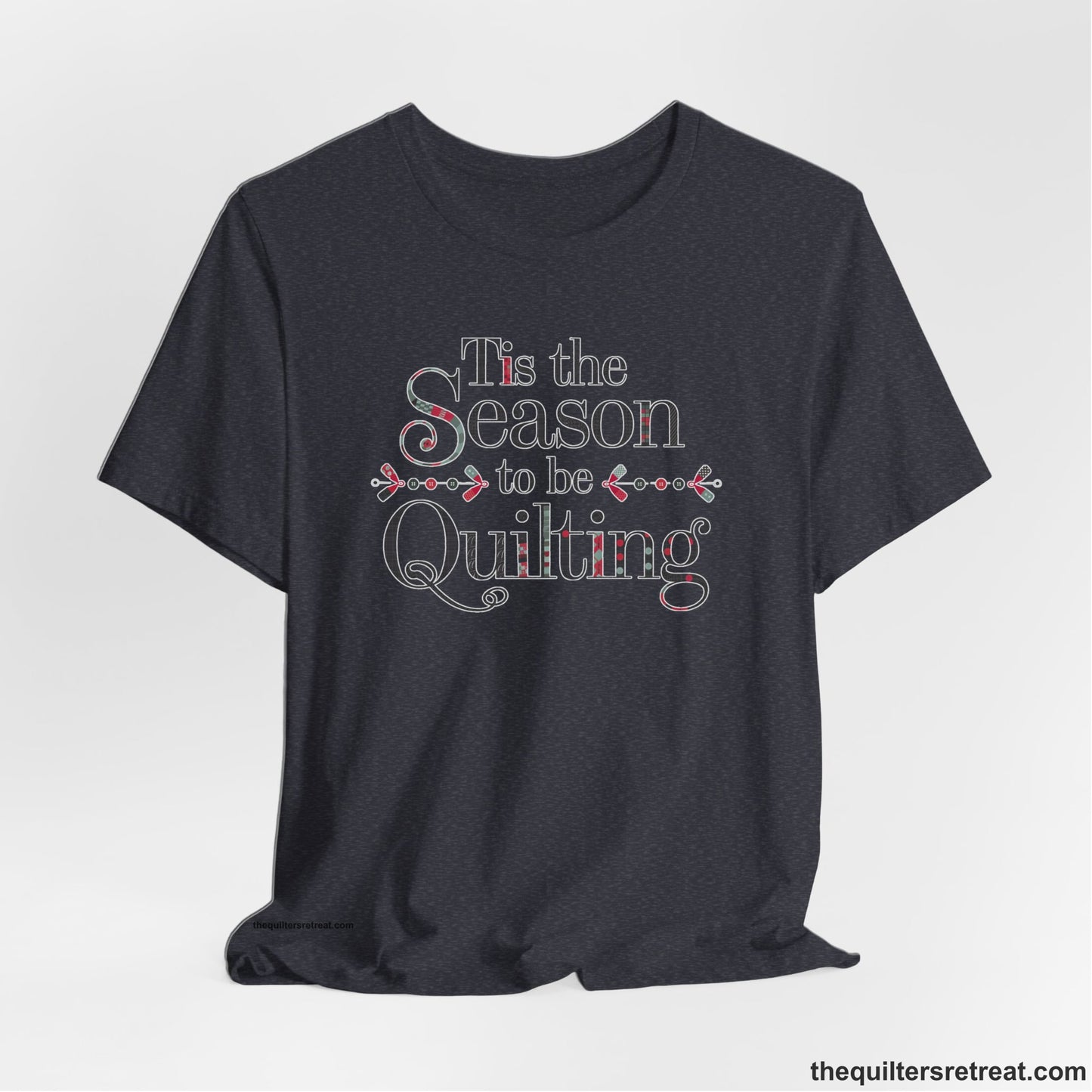A Heather Navy Short Sleeve T-Shirt with a tis the season to be quilting text with festive patchwork pattern in a cheerful style