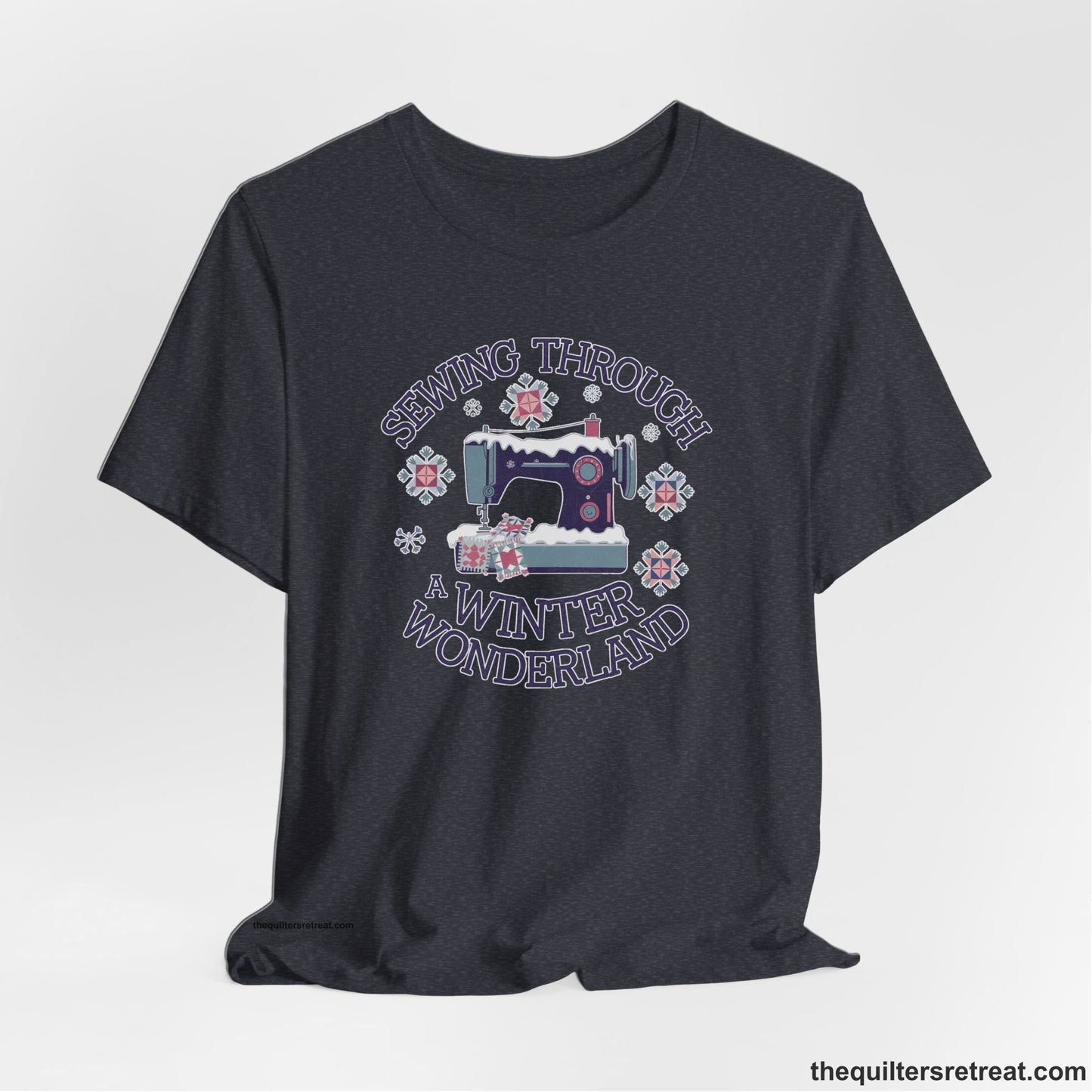 A Heather Navy Short Sleeve T-Shirt with a sewing machine covered in snow with festive quilting elements and "Sewing Through a Winter Wonderland" text