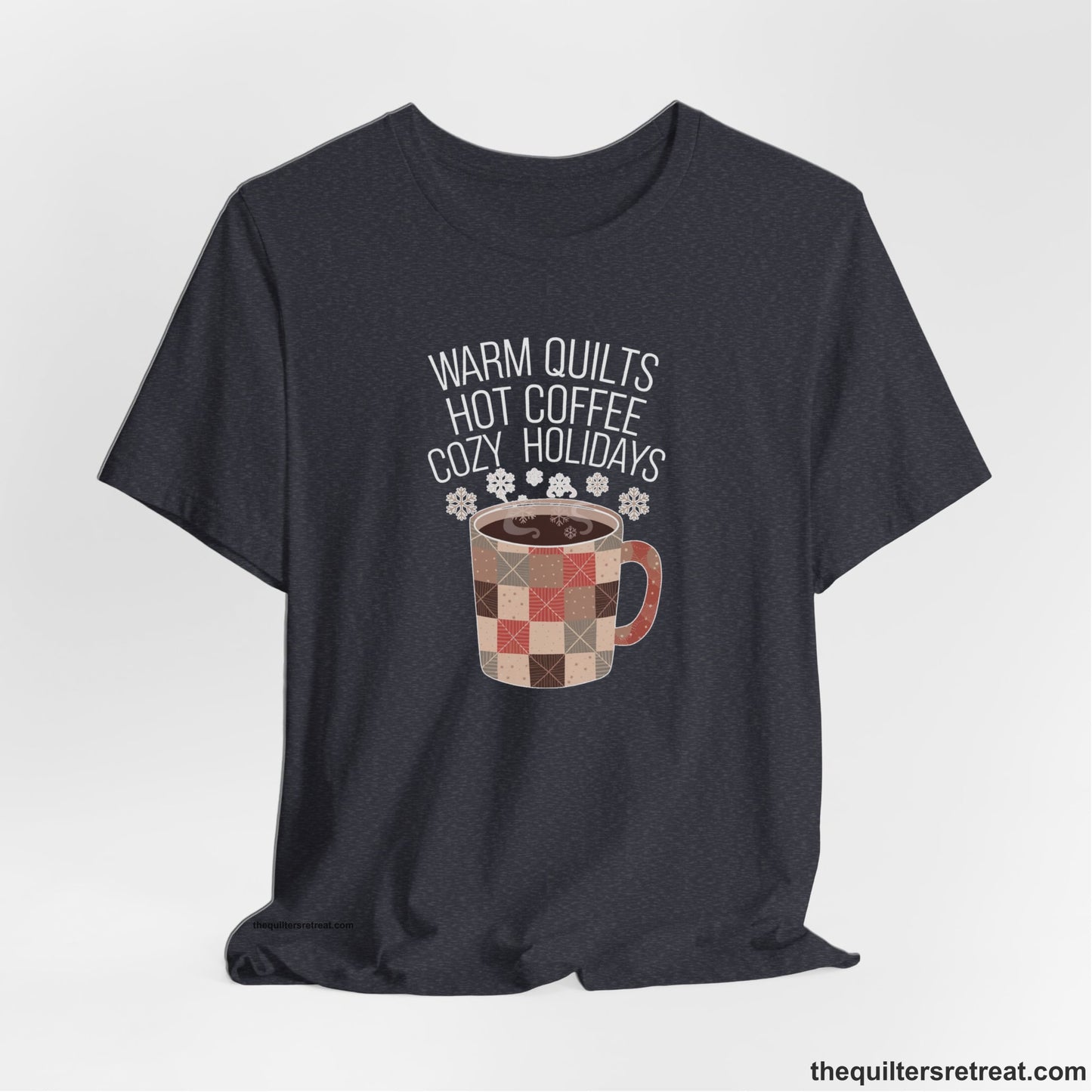 A Heather Navy Short Sleeve T-Shirt with a warm quilts hot coffee cozy holidays text with a patchwork mug and snowflakes