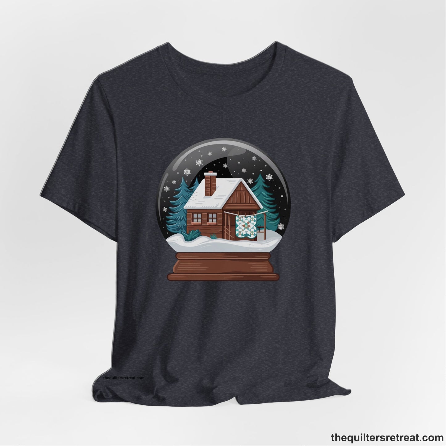 A Heather Navy Short Sleeve T-Shirt with a cabin in a snow globe with snowflakes and trees, in a cozy rustic style