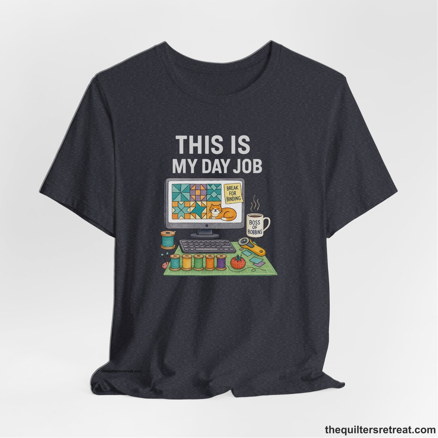 A Heather Navy Short Sleeve T-Shirt with a computer quilt design, cat illustration, "THIS IS MY DAY JOB" text with sewing tools, playful style