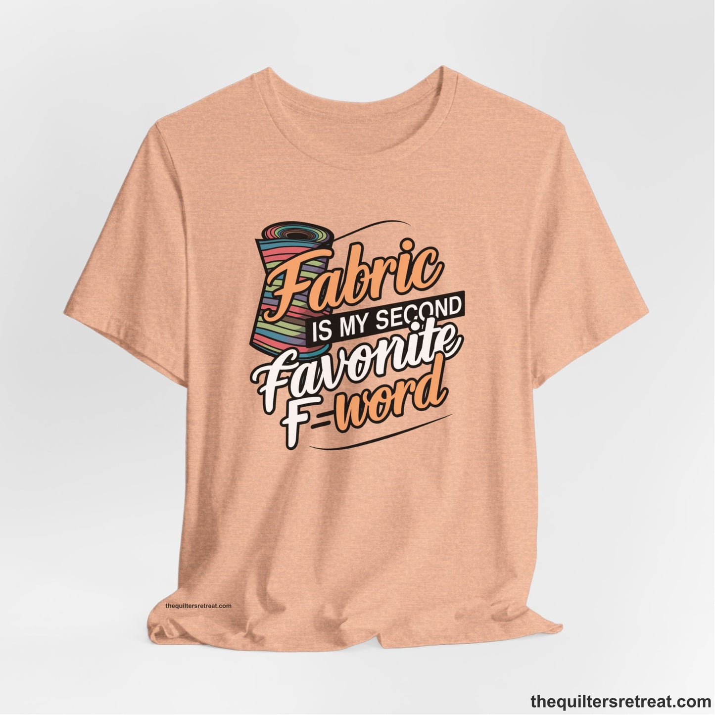 A Heather Peach Short Sleeve T-Shirt with a fabric bolt illustration with bold "Fabric Is My Second Favorite F Word" text