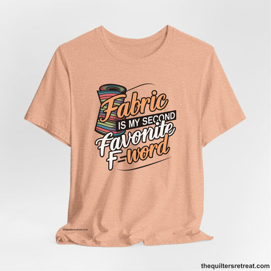 A Heather Peach Short Sleeve T-Shirt with a fabric bolt illustration with bold "Fabric Is My Second Favorite F Word" text