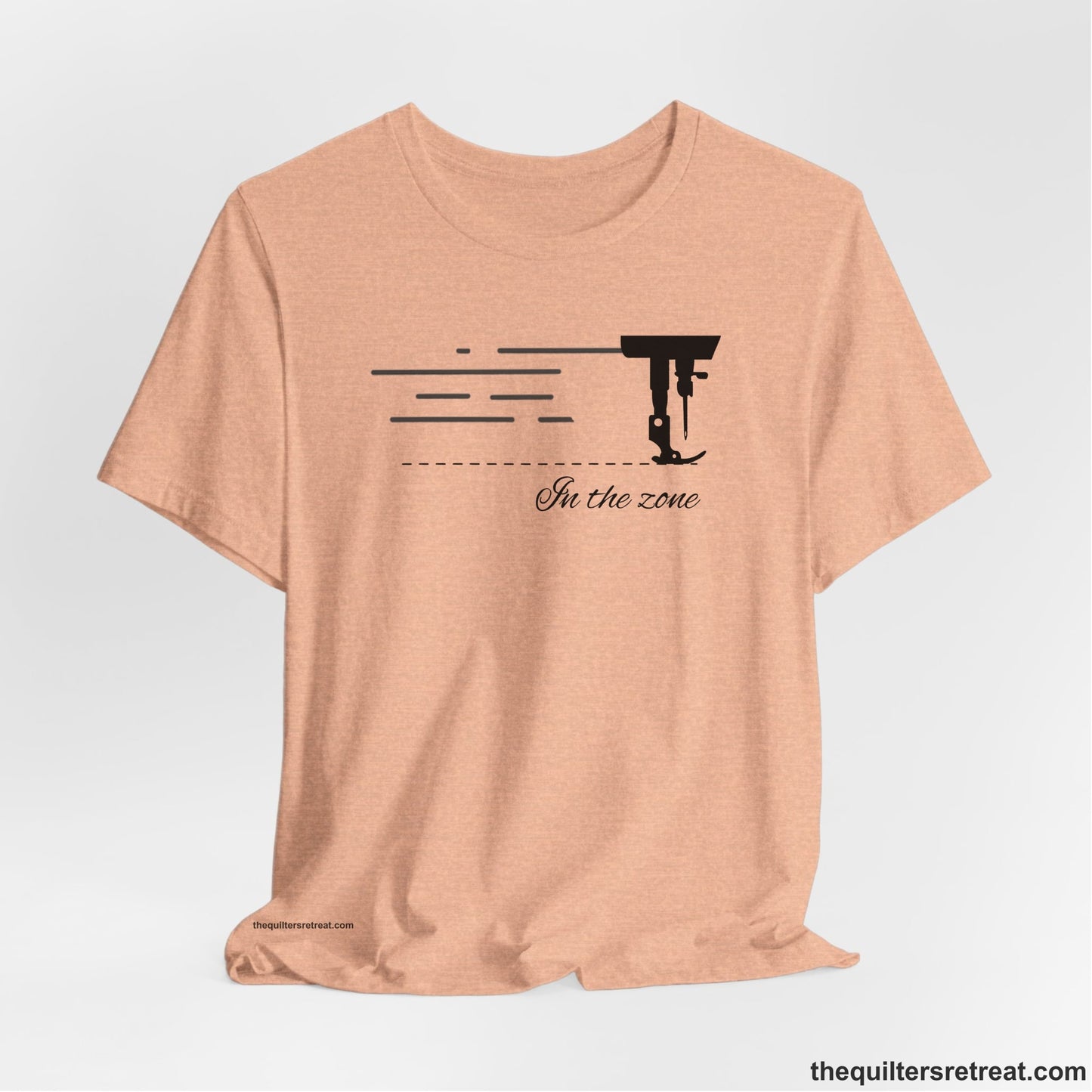 A Heather Peach Short Sleeve T-Shirt with a vintage sewing machine illustration with floral accents and "Sewing Mends the Soul" text