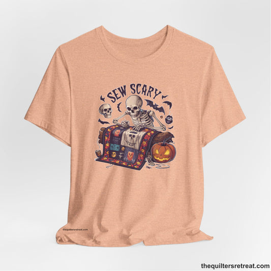 A Heather Peach Short Sleeve T-Shirt with a skeleton quilting with spooky accents and "Sew Scary" text in a Halloween theme