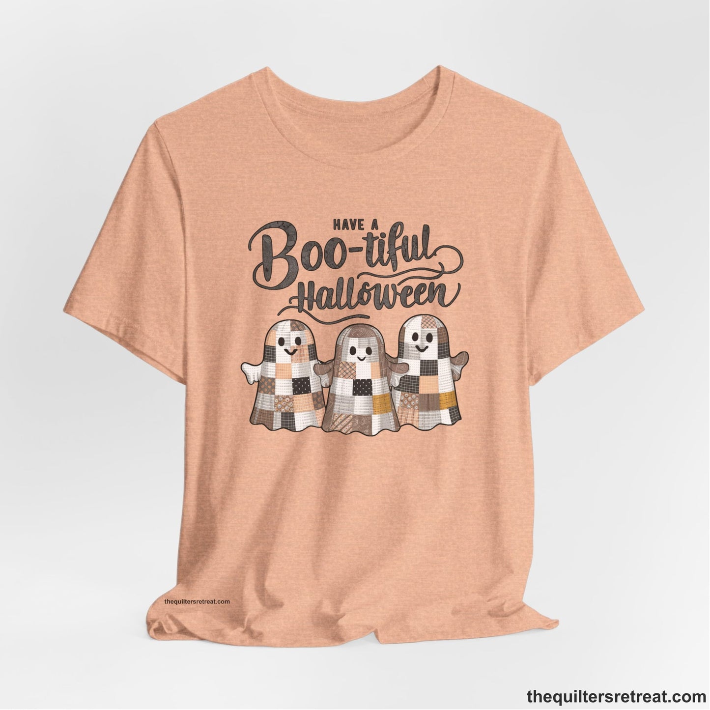 A Heather Peach Short Sleeve T-Shirt with a cute patchwork ghosts with "Boo-tiful Halloween" text in a playful style