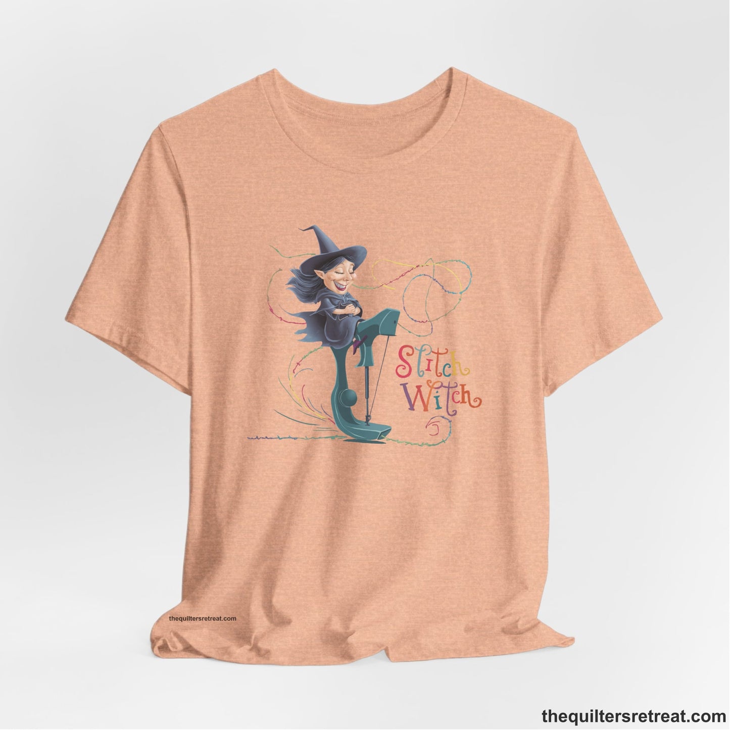 A Heather Peach Short Sleeve T-Shirt with a witch on vintage sewing machine with "Stitch Witch" text in playful, colorful style