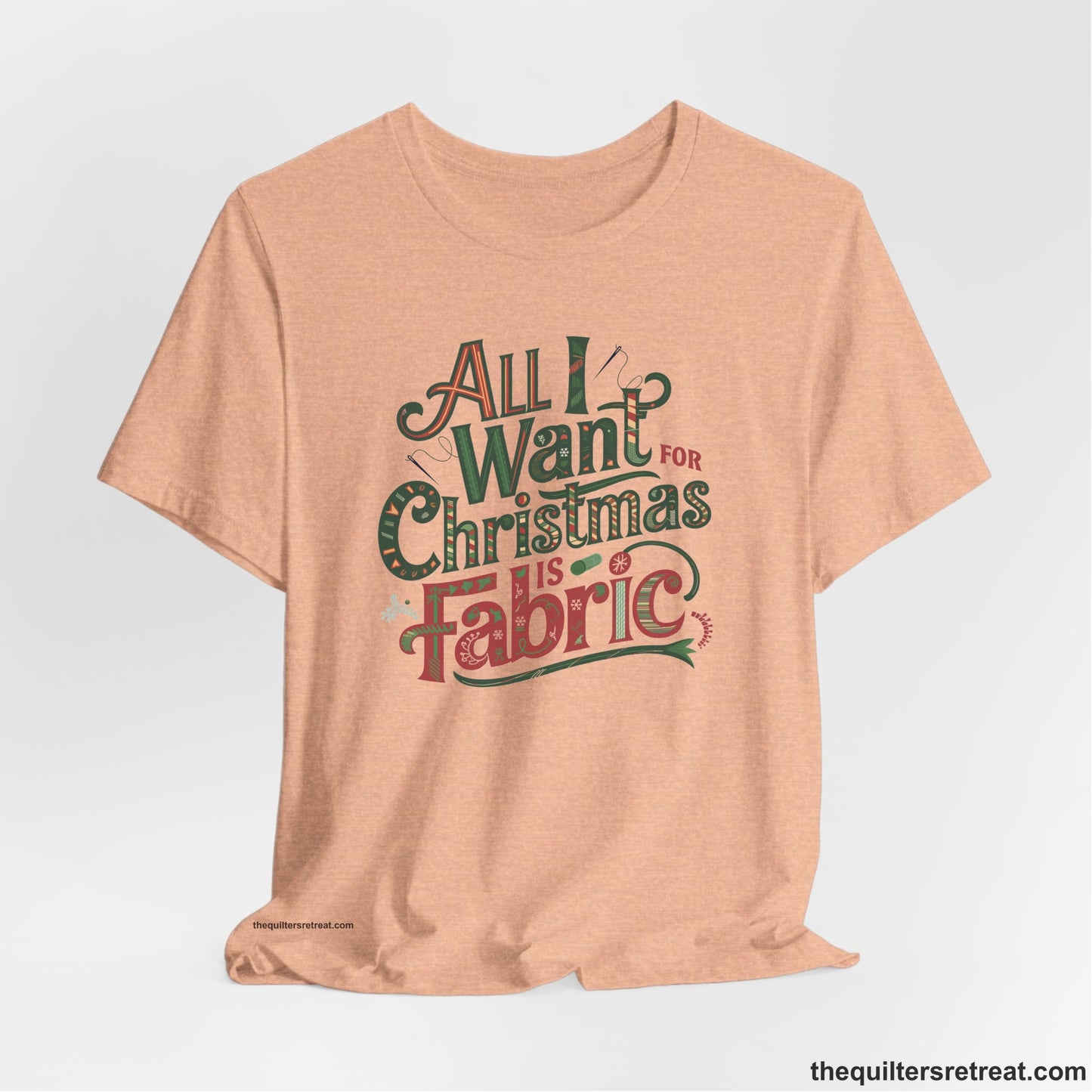 A Heather Peach Short Sleeve T-Shirt with a vintage holiday text "All I Want for Christmas is Fabric" with festive motifs