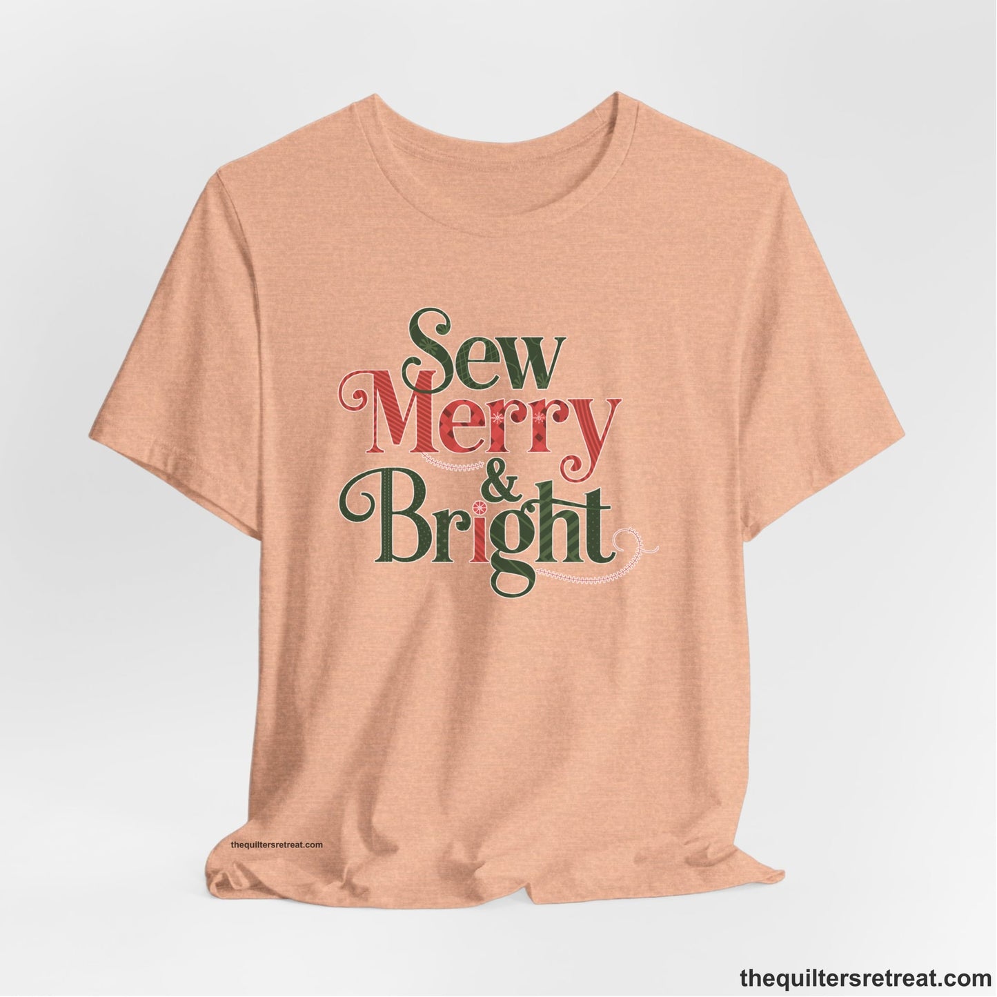 A Heather Peach Short Sleeve T-Shirt with a festive "Sew Merry & Bright" text with decorative holiday patterns