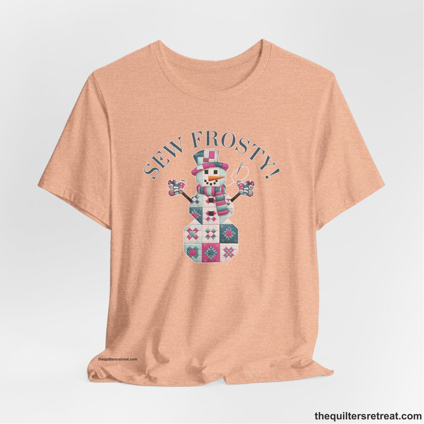 A Heather Peach Short Sleeve T-Shirt with a snowman quilt pattern with "Sew Frosty!" text in a crafty style