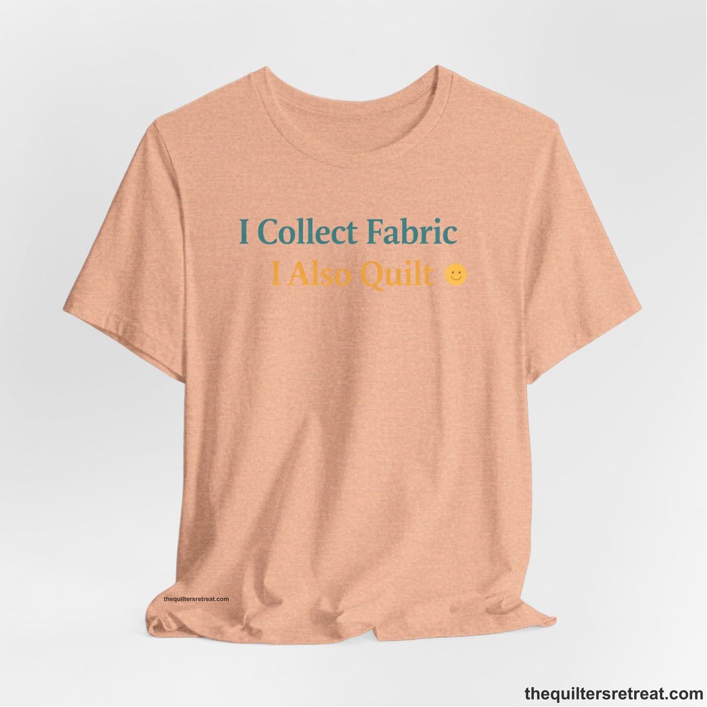 A Heather Peach Short Sleeve T-Shirt with a Colorful text saying "I Collect Fabric I Also Quilt" with a playful, cheerful vibe.