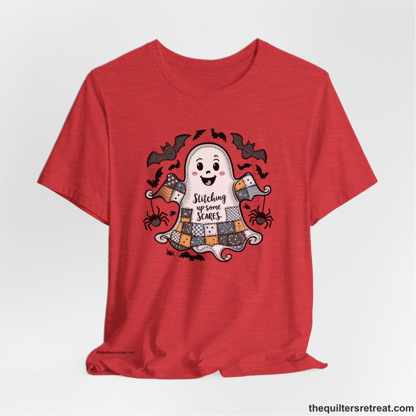 A Heather Red Short Sleeve T-Shirt with a cute patchwork ghost with "Stitching up some Scares" text and playful bats in a whimsical style
