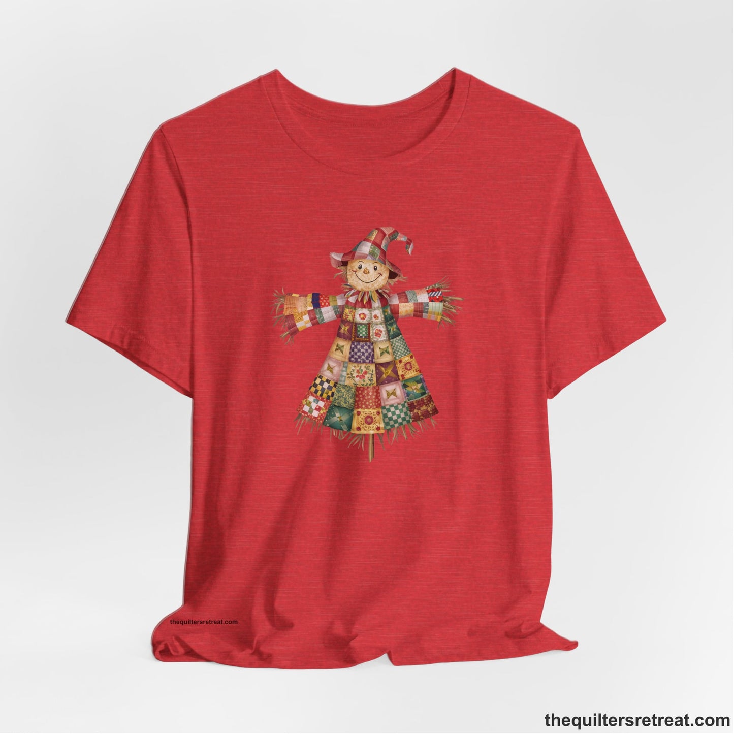 A Heather Red Short Sleeve T-Shirt with a patchwork scarecrow with a cheerful face in a whimsical style