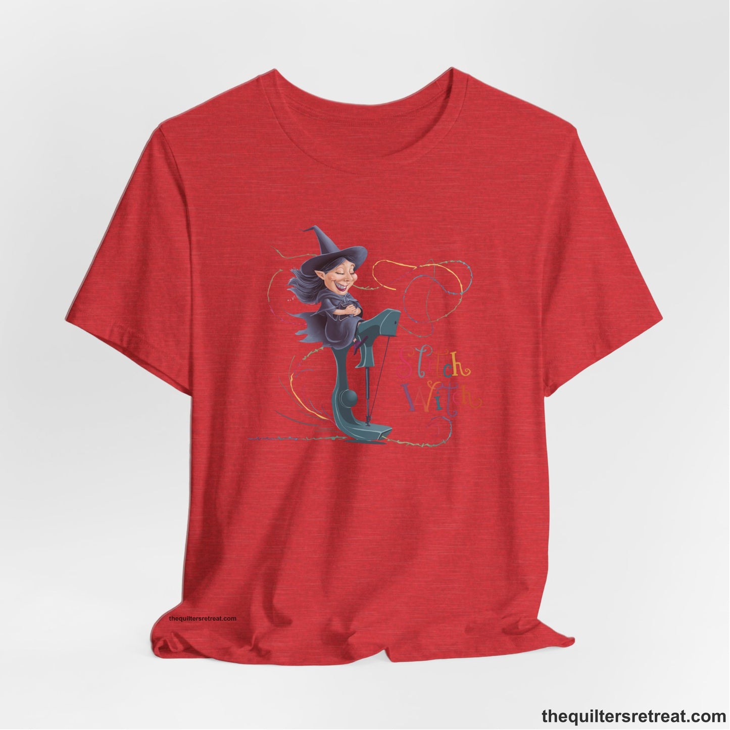 A Heather Red Short Sleeve T-Shirt with a witch on vintage sewing machine with "Stitch Witch" text in playful, colorful style