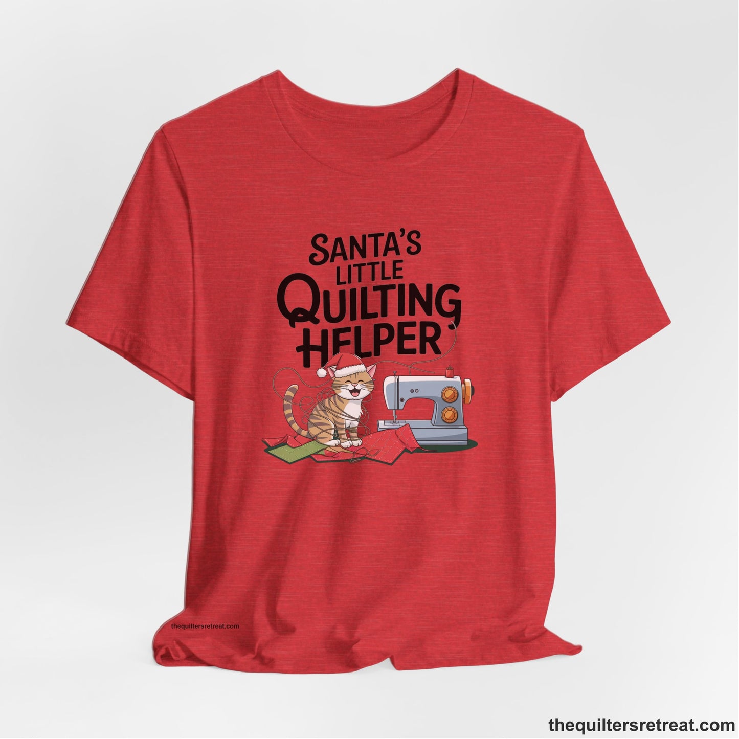 A Heather Red Short Sleeve T-Shirt with a santa-hat-wearing kitten with a sewing machine and "Santa's Little Quilting Helper" text in playful style