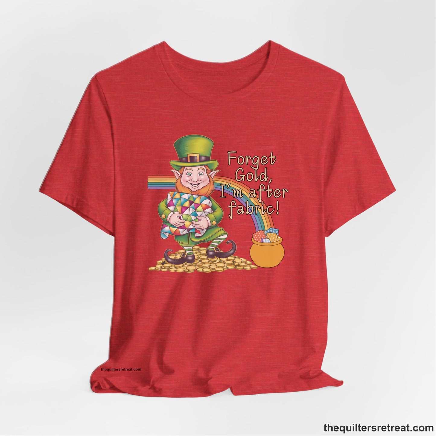 A Heather Red Short Sleeve T-Shirt with a leprechaun with colorful quilt and rainbow, whimsical "Forget Gold, I'm after fabric!" text