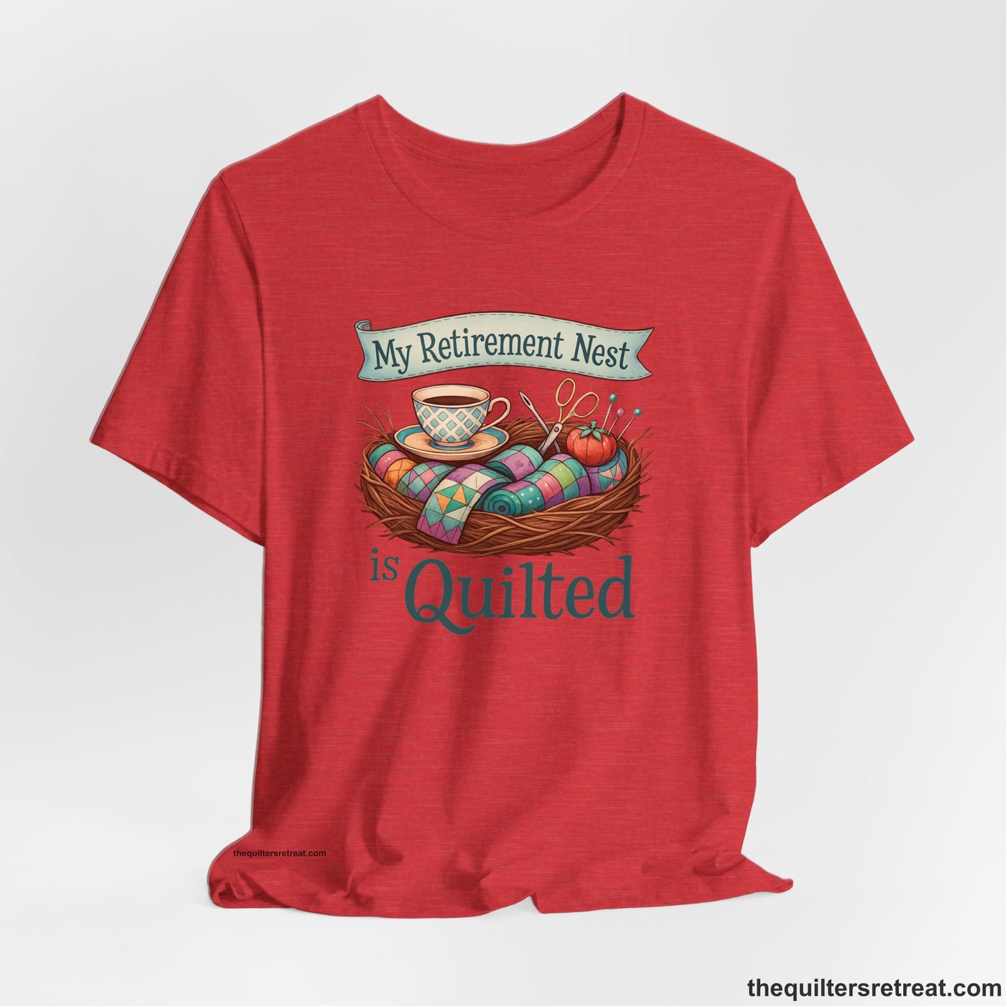 A Heather Red Short Sleeve T-Shirt with a My Retirement Nest is Quilted text with a cozy sewing elements illustration