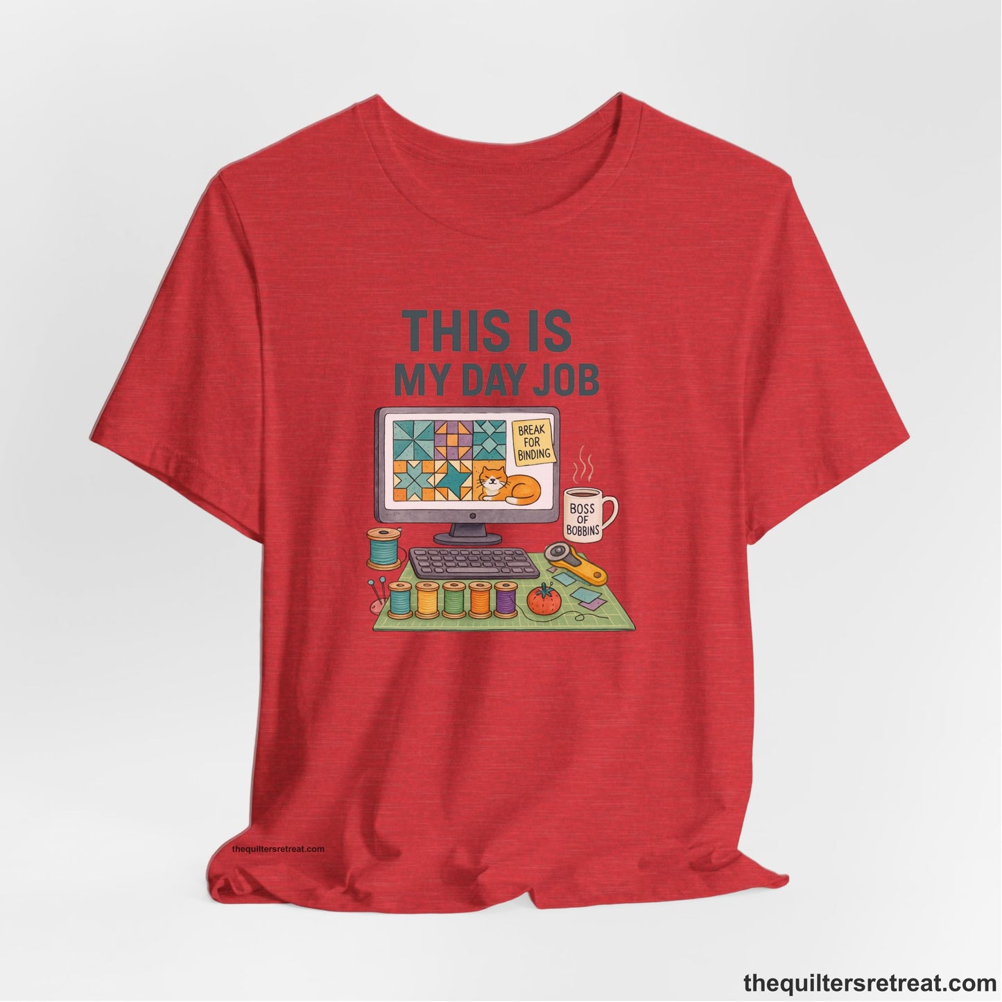 A Heather Red Short Sleeve T-Shirt with a computer quilt design, cat illustration, "THIS IS MY DAY JOB" text with sewing tools, playful style
