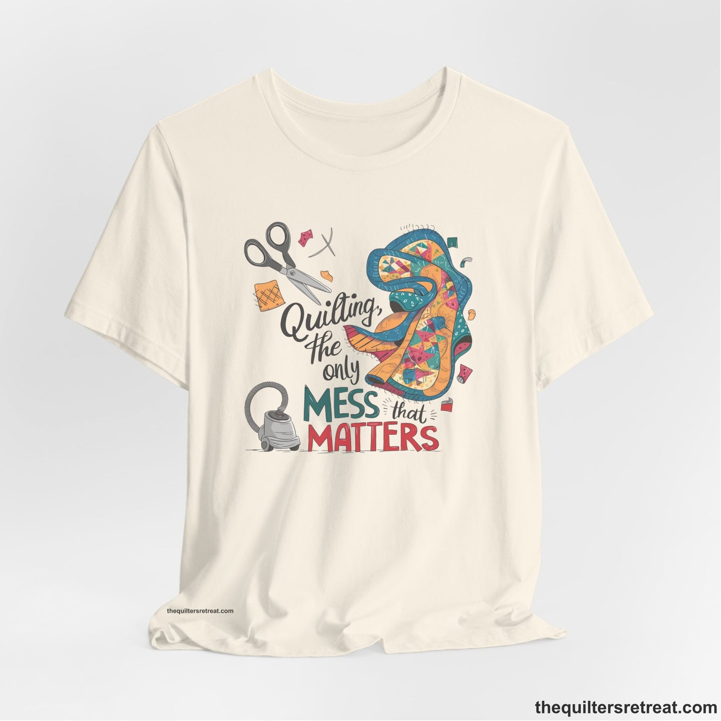 A Natural Short Sleeve T-Shirt with a quilting tools and patchwork pieces with bold "Quilting, the only mess that matters" text