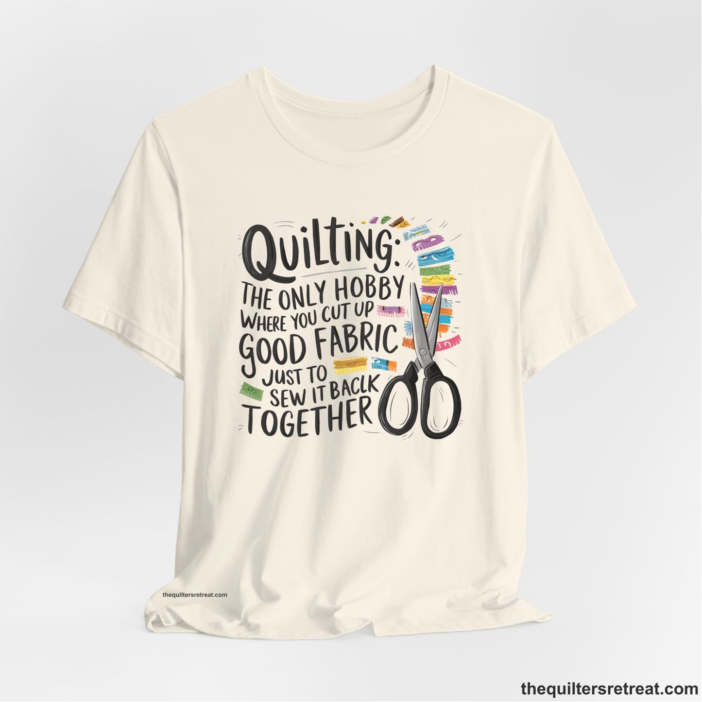 A Natural Short Sleeve T-Shirt with a quilting-themed text with colorful fabric pieces and scissors in a whimsical style