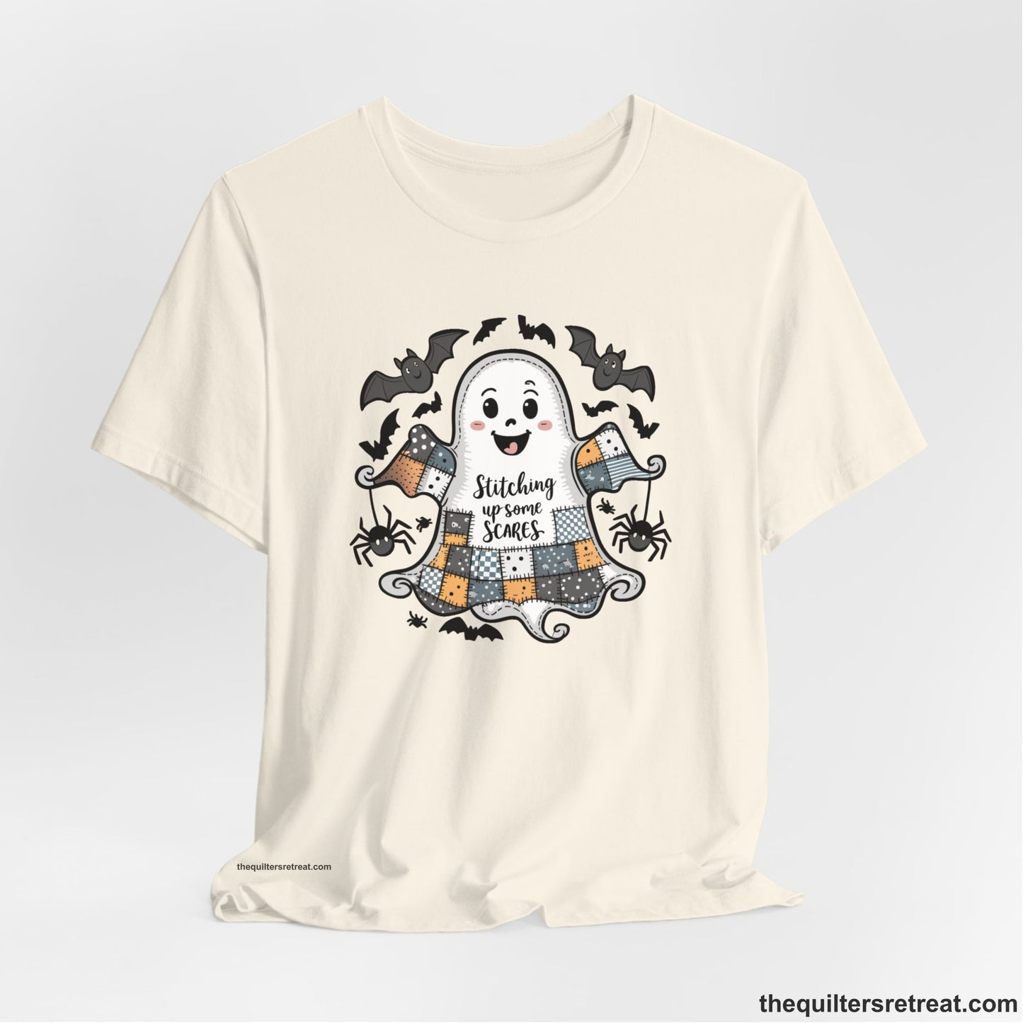 A Natural Short Sleeve T-Shirt with a cute patchwork ghost with "Stitching up some Scares" text and playful bats in a whimsical style