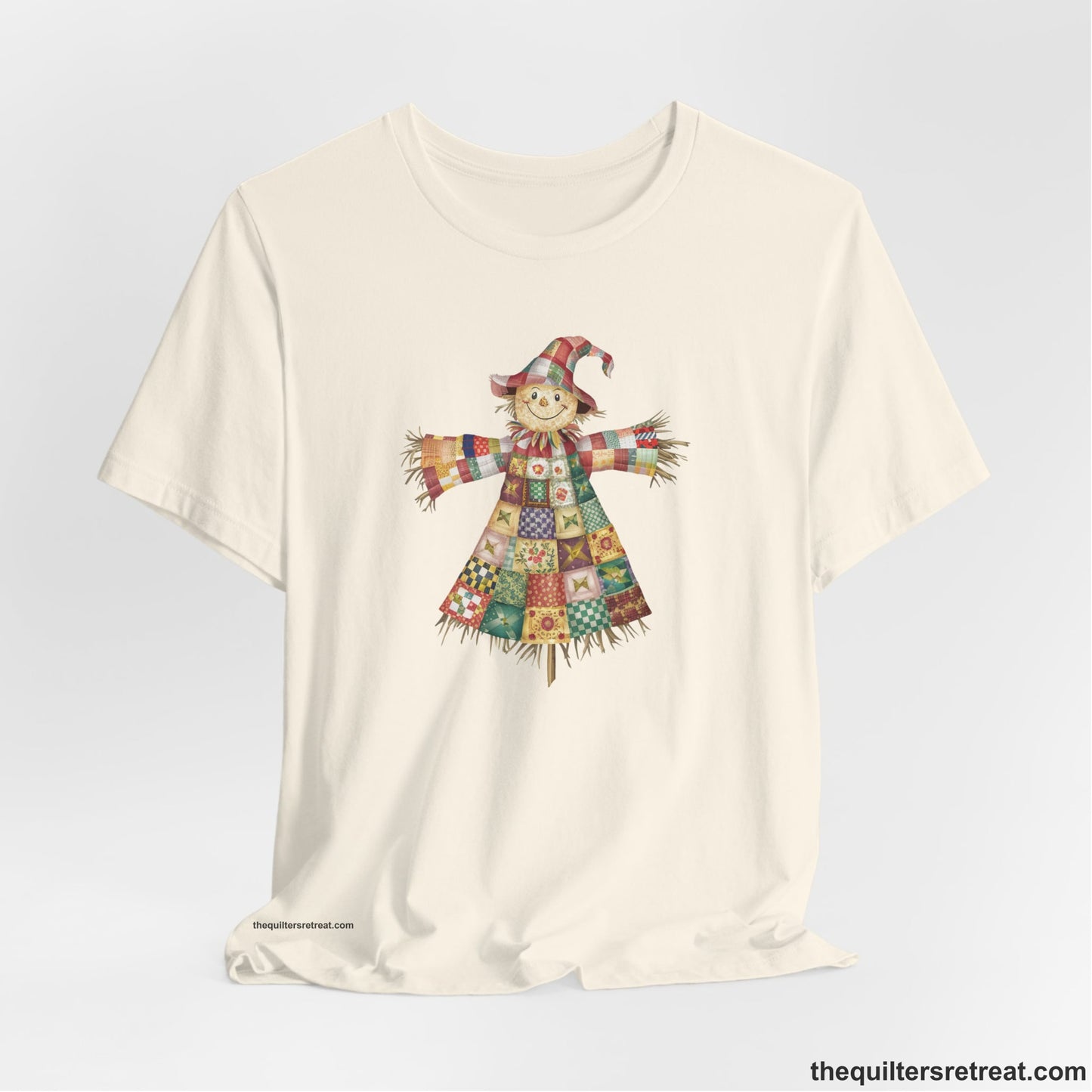 A Natural Short Sleeve T-Shirt with a patchwork scarecrow with a cheerful face in a whimsical style