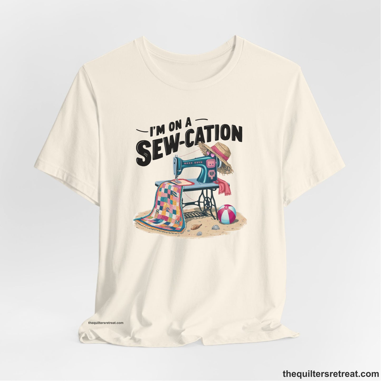A Natural Short Sleeve T-Shirt with a vintage sewing machine with colorful quilt, beach items, and "I'm On A Sew-Cation" text