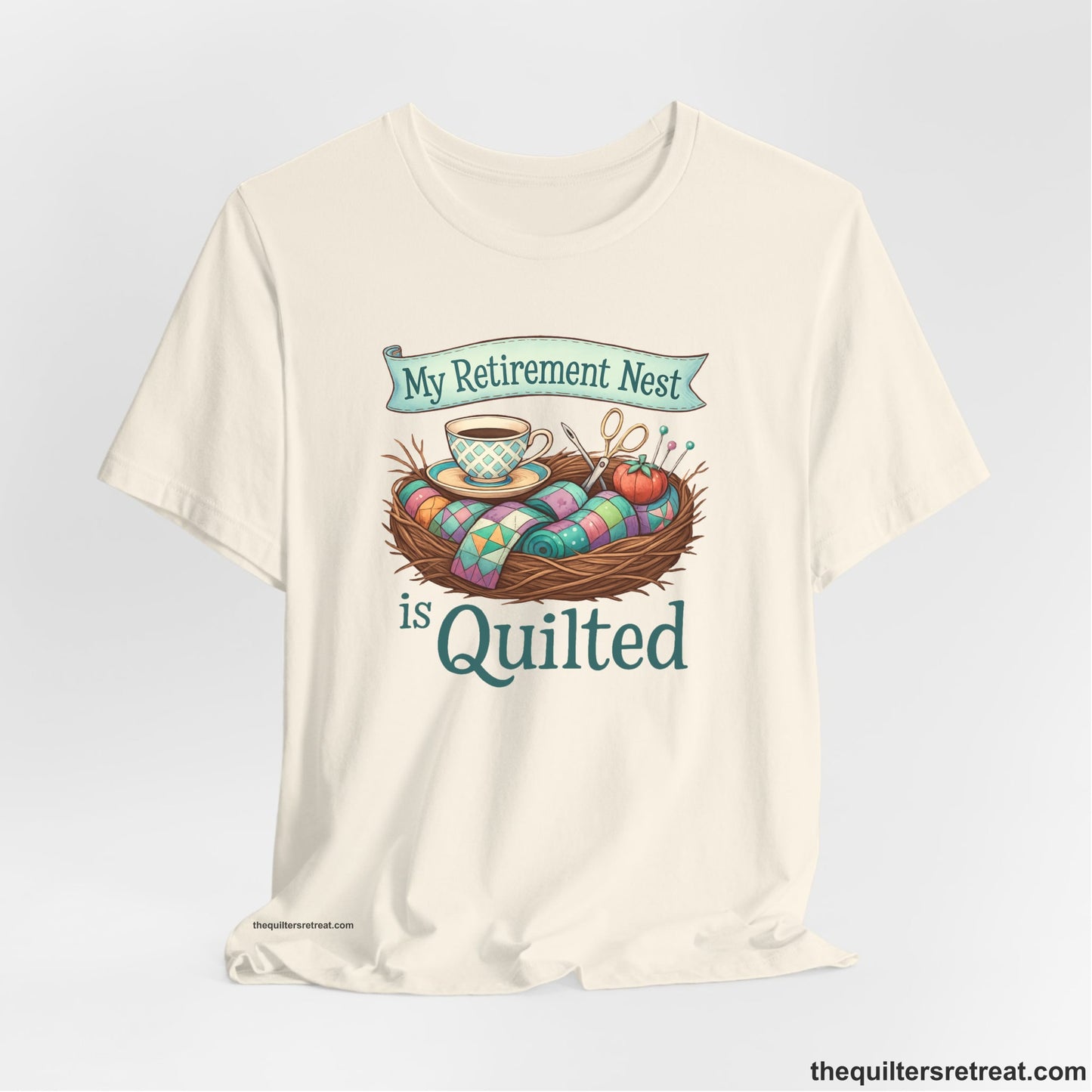 A Natural Short Sleeve T-Shirt with a My Retirement Nest is Quilted text with a cozy sewing elements illustration