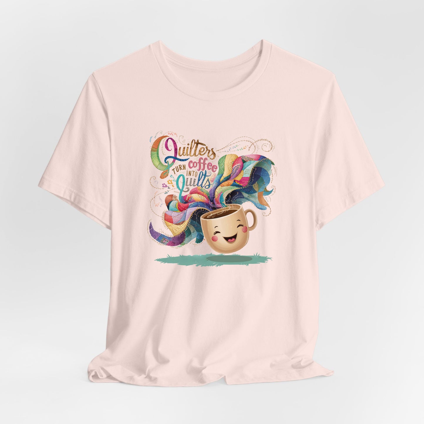 A Soft Pink Short Sleeve T-Shirt with a quirky "Quilters Turn Coffee into Quilts" text with vibrant swirling patterns