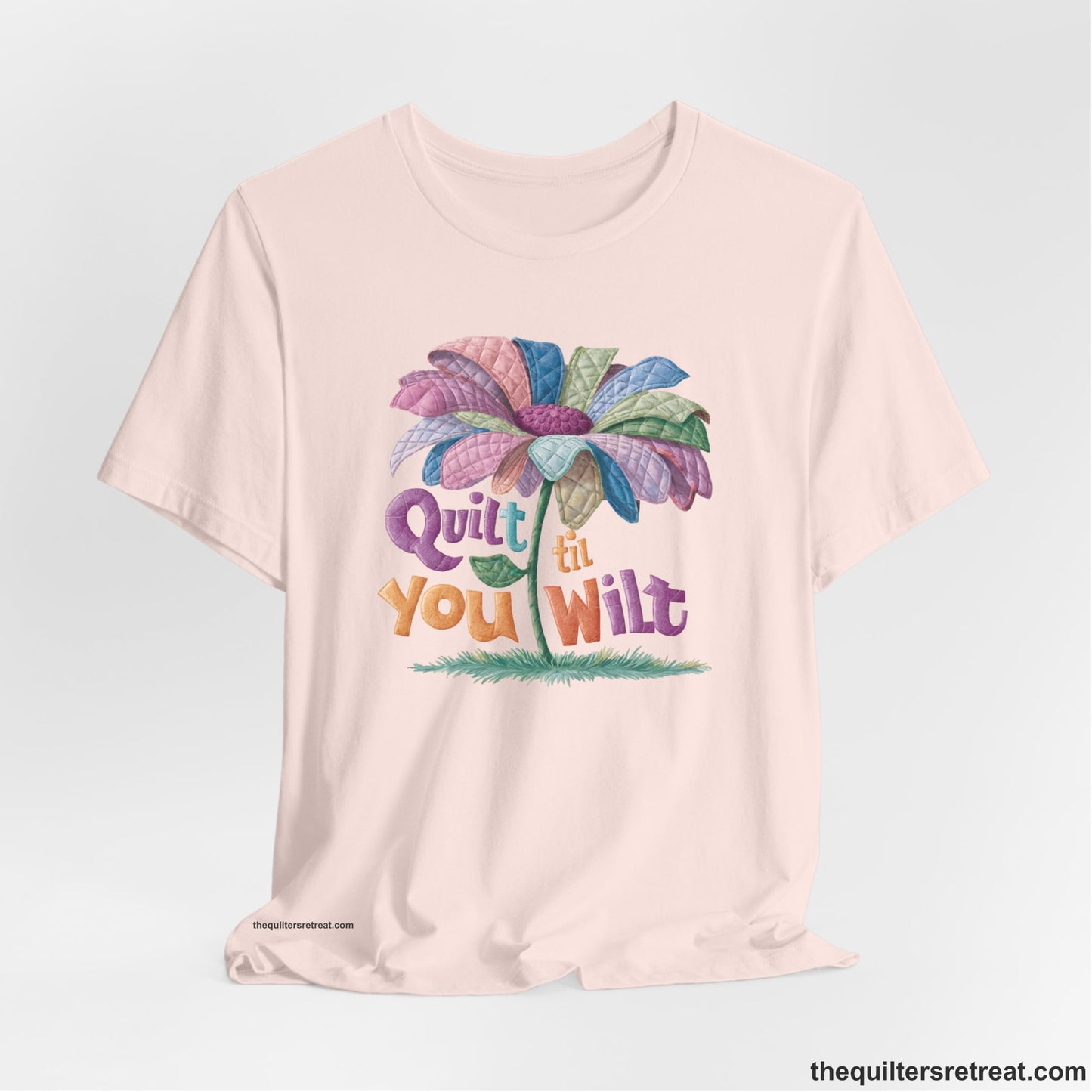 A Soft Pink Short Sleeve T-Shirt with a whimsical quilted flower with bold "Quilt til You Wilt" text