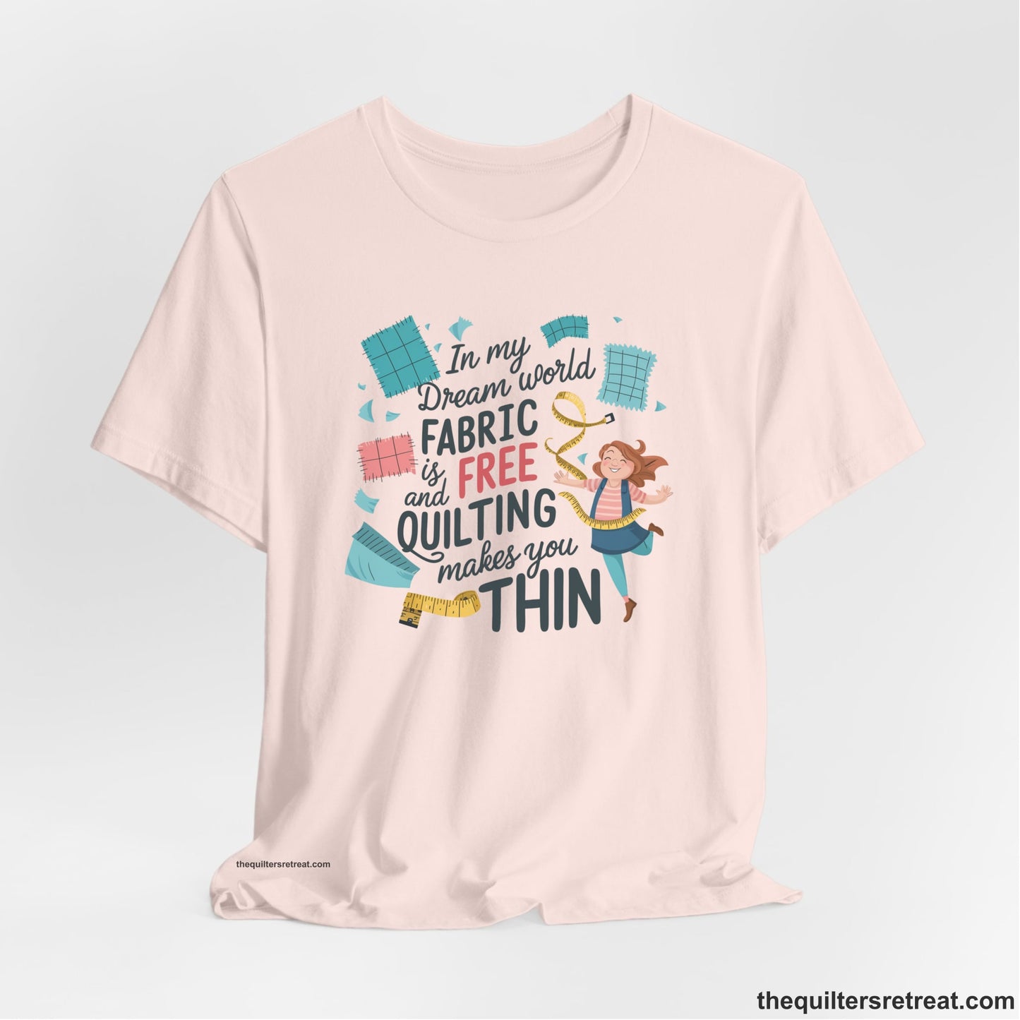 A Soft Pink Short Sleeve T-Shirt with a inspirational quilting text with playful seamstress and colorful fabric scraps in whimsical style