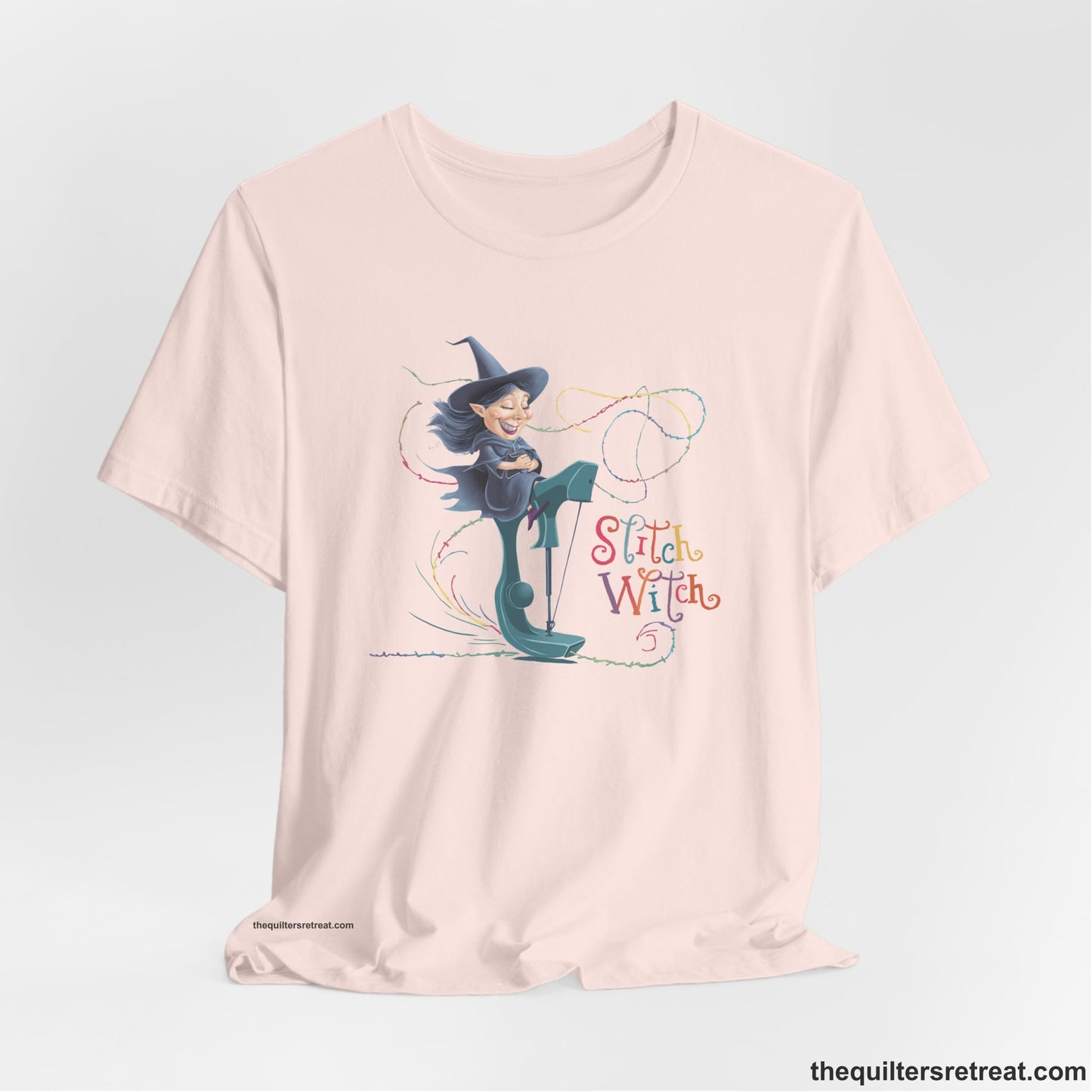 A Soft Pink Short Sleeve T-Shirt with a witch on vintage sewing machine with "Stitch Witch" text in playful, colorful style