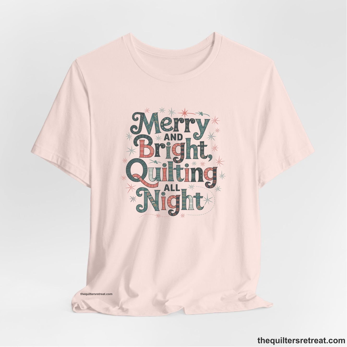 A Soft Pink Short Sleeve T-Shirt with a Merry and Bright Quilting All Night text with festive patterns and stars in a whimsical style