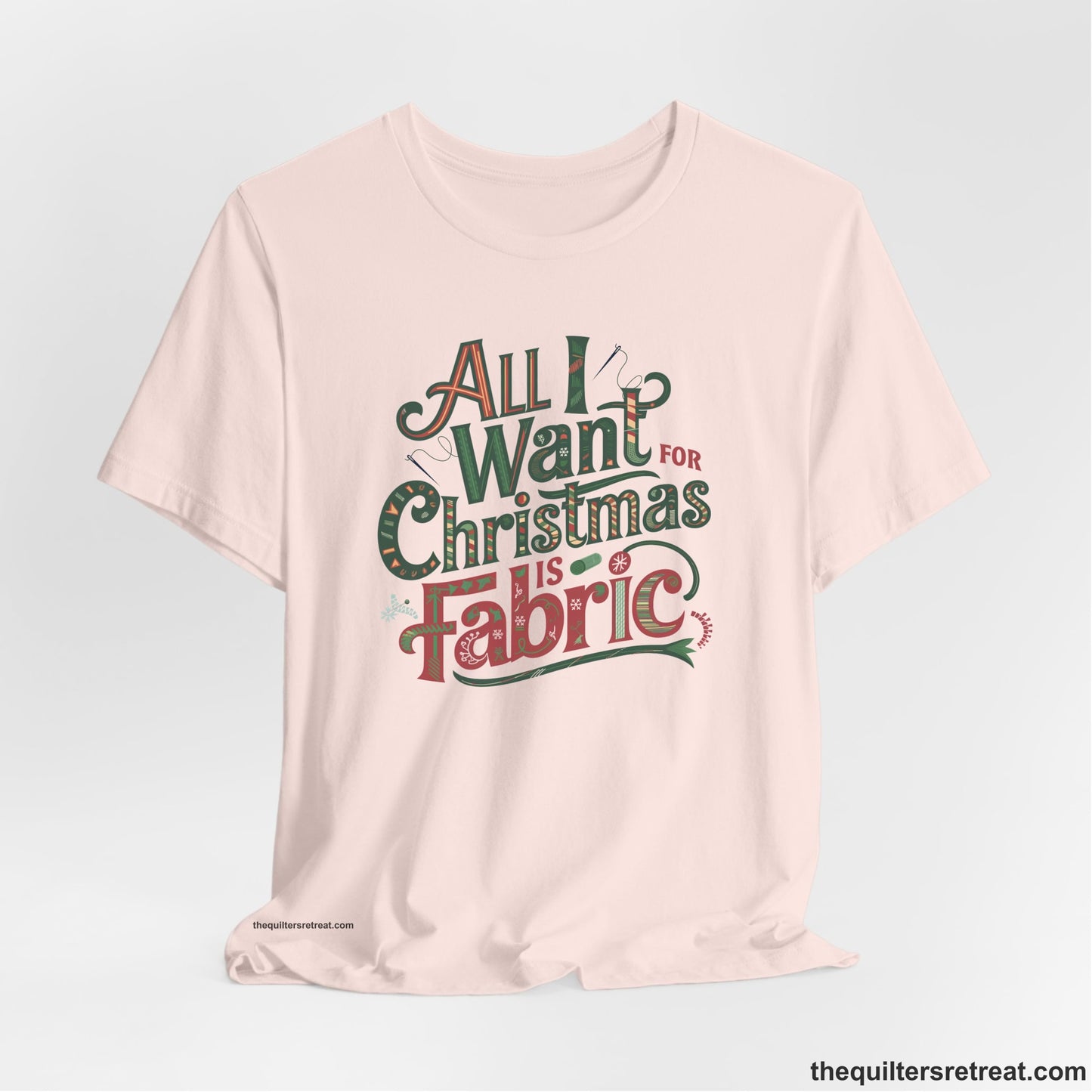 A Soft Pink Short Sleeve T-Shirt with a vintage holiday text "All I Want for Christmas is Fabric" with festive motifs