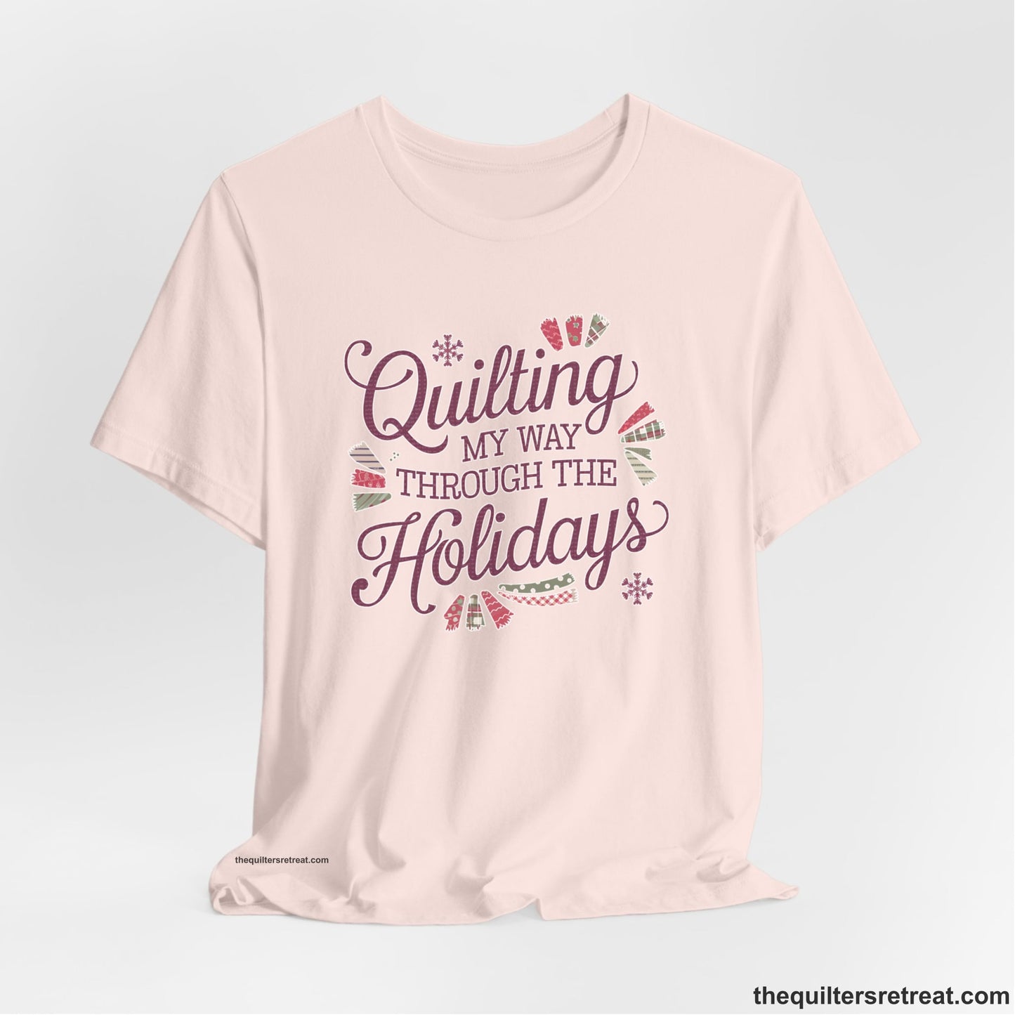 A Soft Pink Short Sleeve T-Shirt with a quilting-themed text in festive colors with decorative quilt patterns