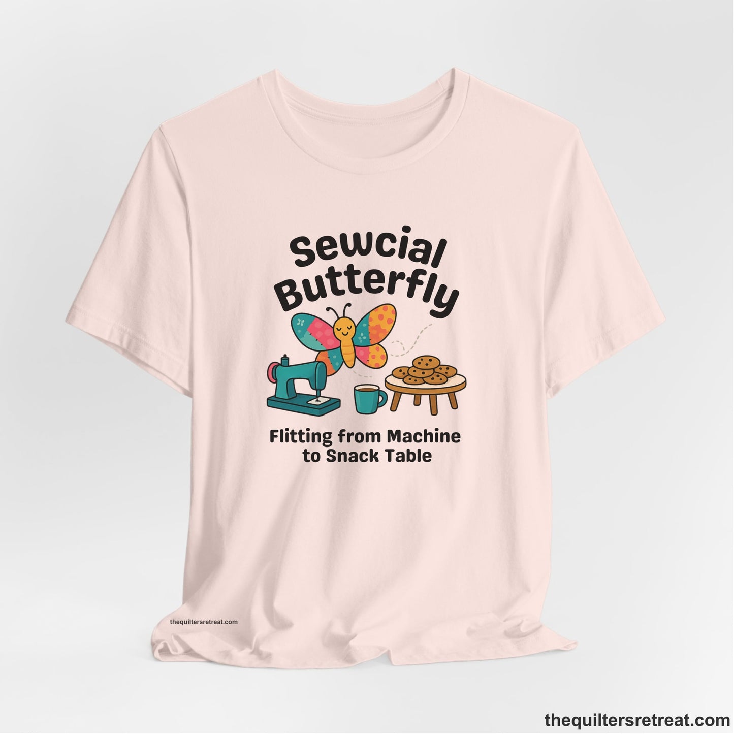 A Soft Pink Short Sleeve T-Shirt with a playful butterfly near sewing machine with cookies and coffee doodle design