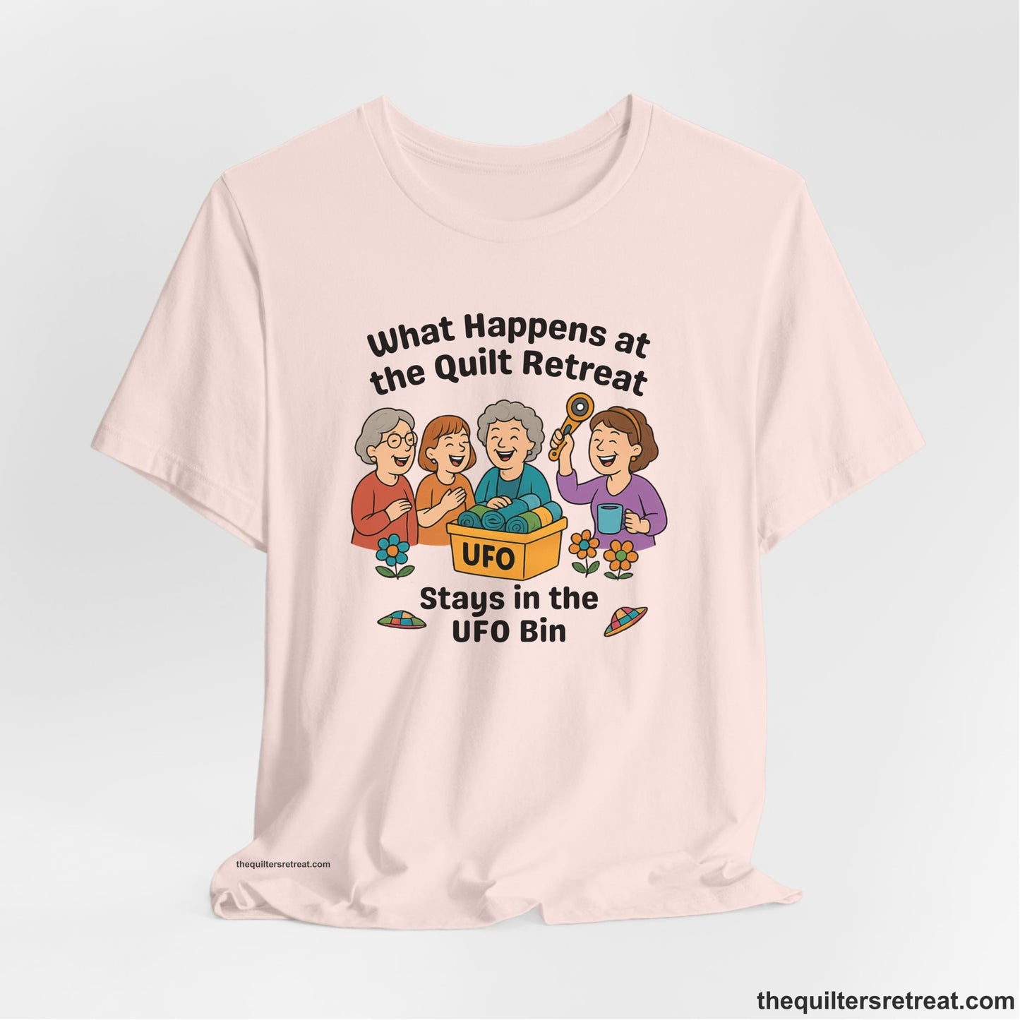 A Soft Pink Short Sleeve T-Shirt with a four smiling women with unfinished fabric objects and playful "UFO" text in a cartoon style